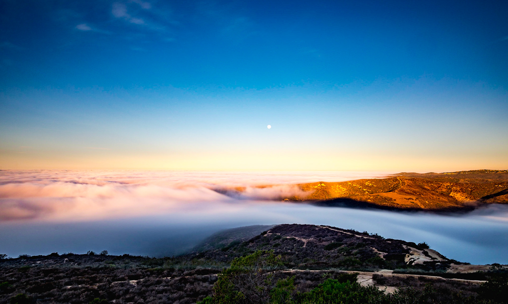 Looking out over Laguna Beach at the 2016 Super Moon, the fog is rolling into the canyon, while the sun rises behind to eventually burn off the fog.  This was a slow exposure trying to capture the fluidity of the clouds.