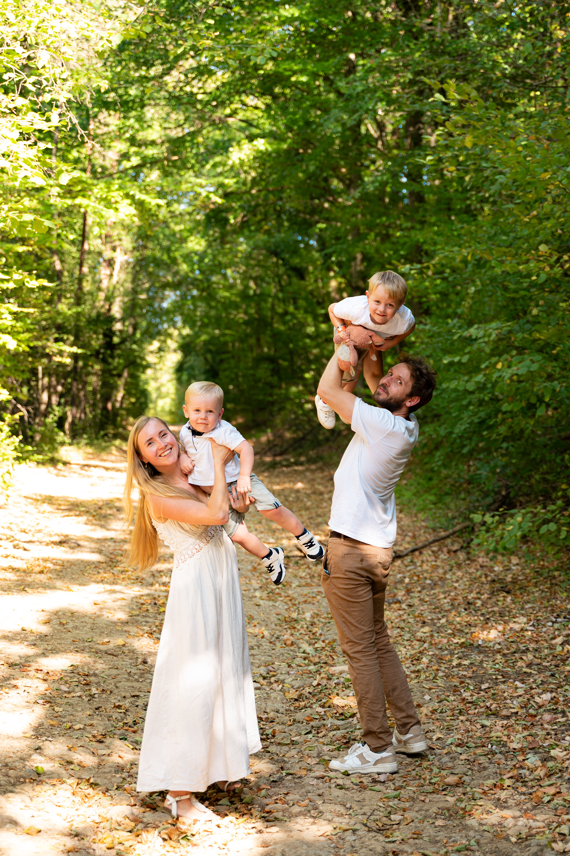 Parents jouant avec leurs deux enfants lors d’une séance photo famille en pleine nature.