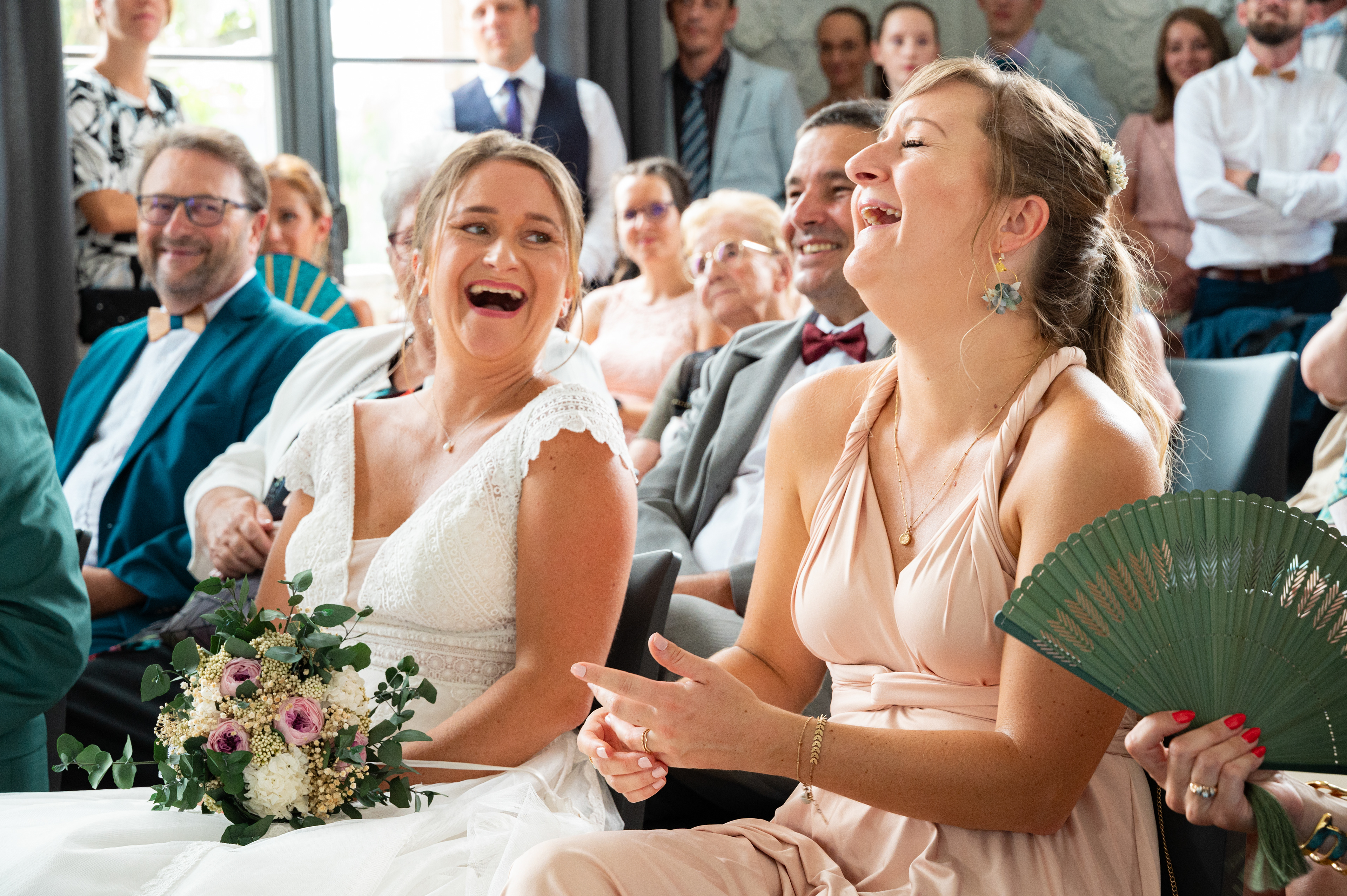éclat de rire entre la mariée et sa témoin pris sur le vif pendant la cérémonie civile de mariage