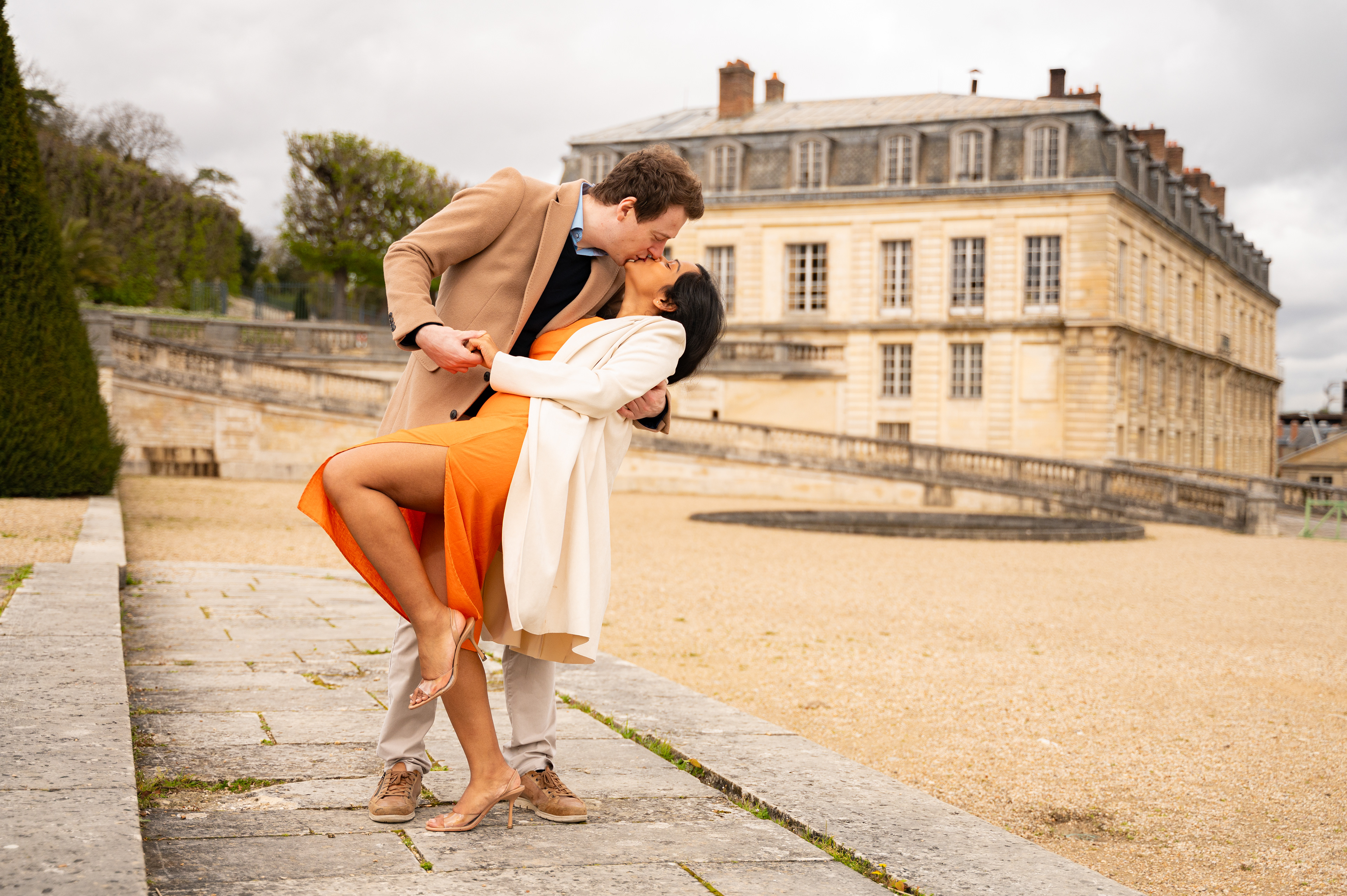 un couple s'embrasse devant le château de saint-cloud pendant une séance engagement