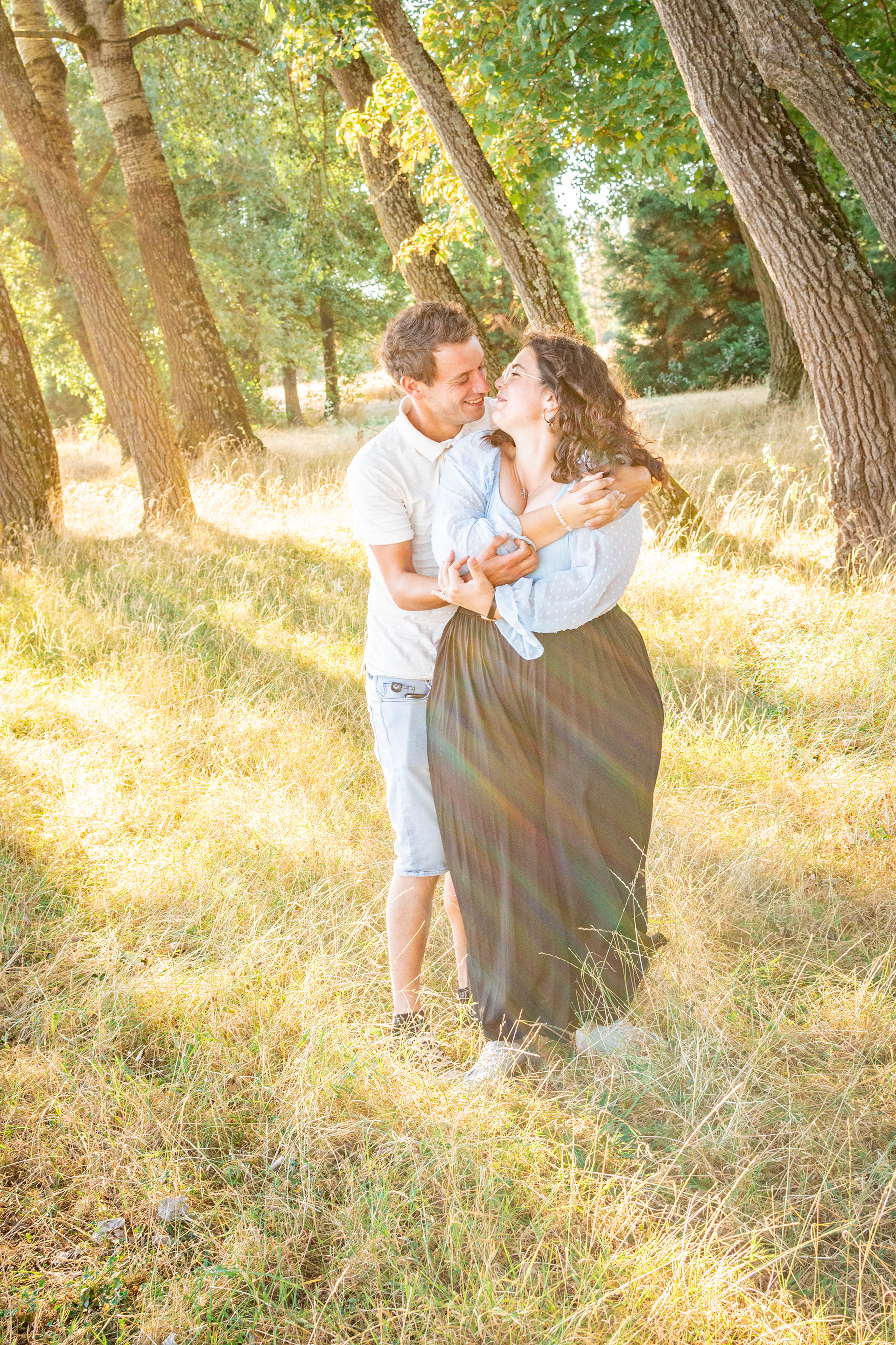 les futurs mariés échangent un regard complice baignés par les rayons de soleil matinaux pendant la séance engagement