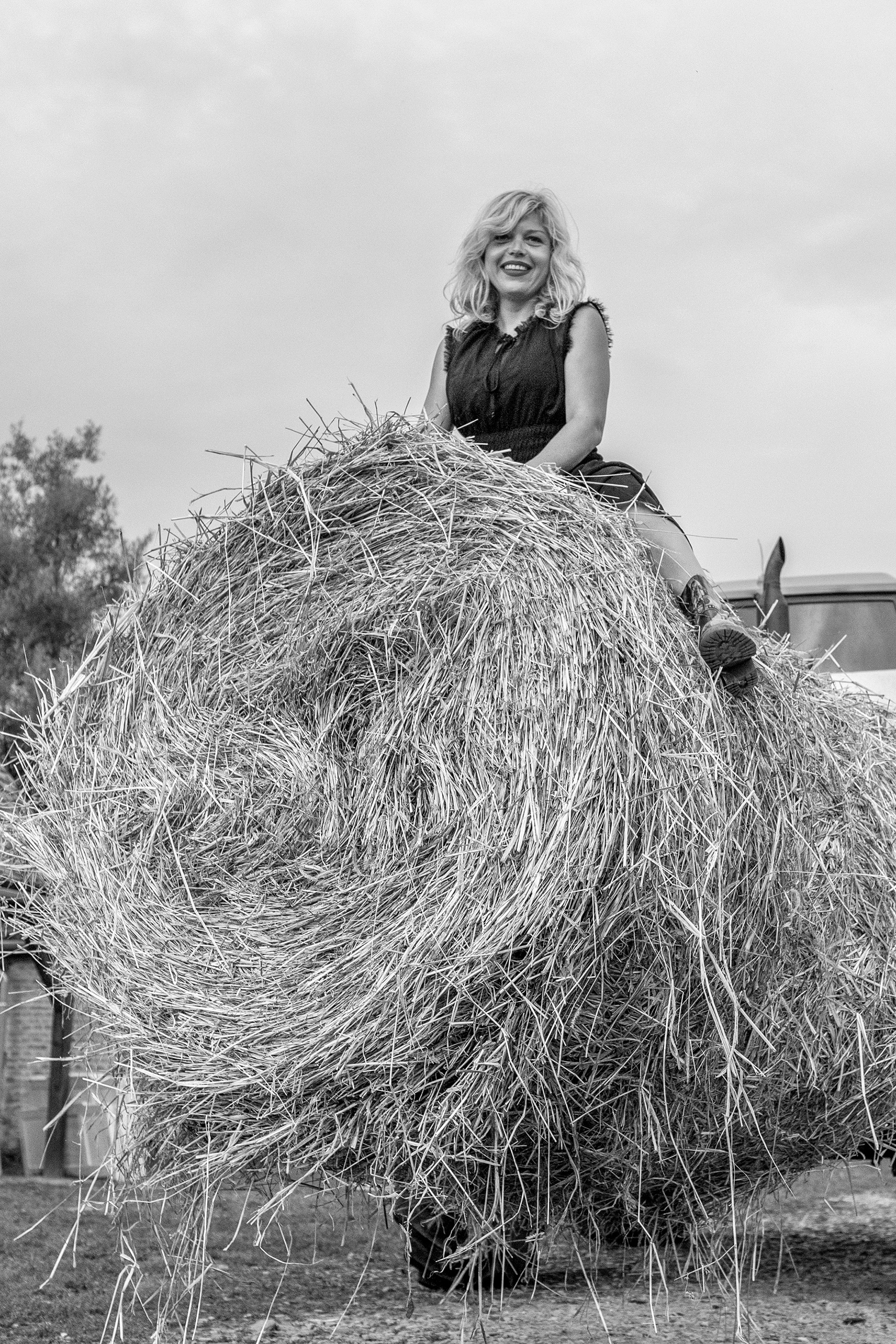 girl standing on haystack in rural landscape