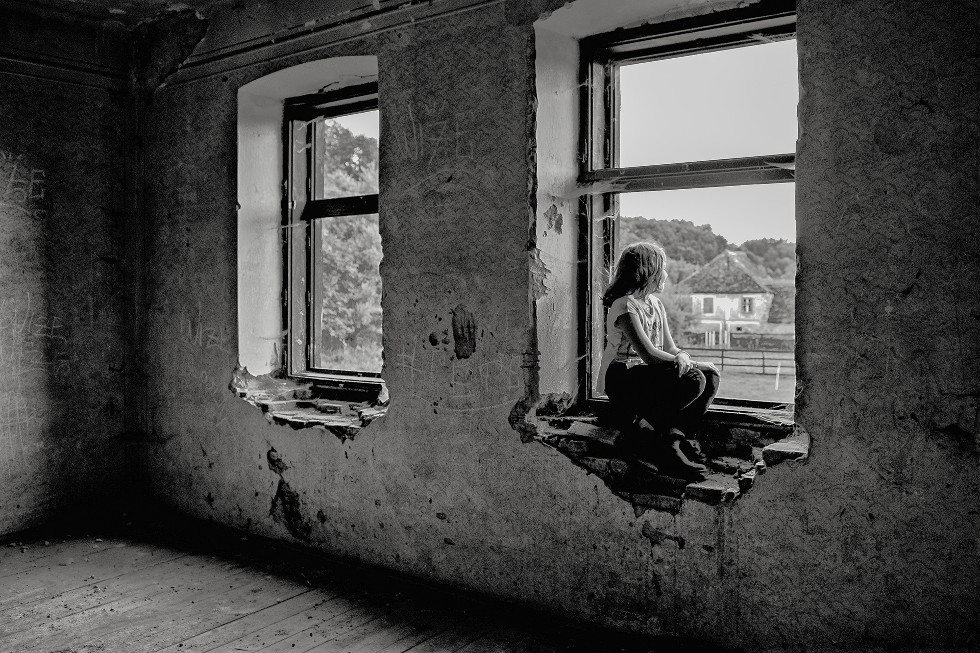 girl sitting by window inside rural house