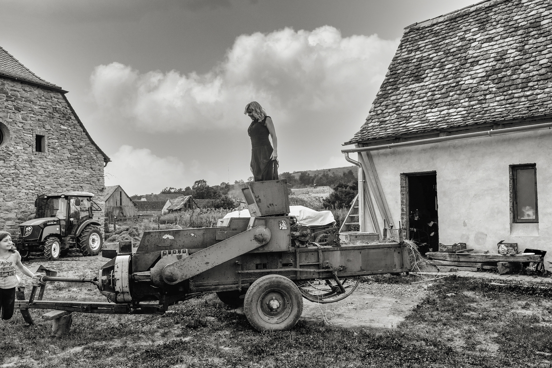 girl sitting on farm machinery in village yard