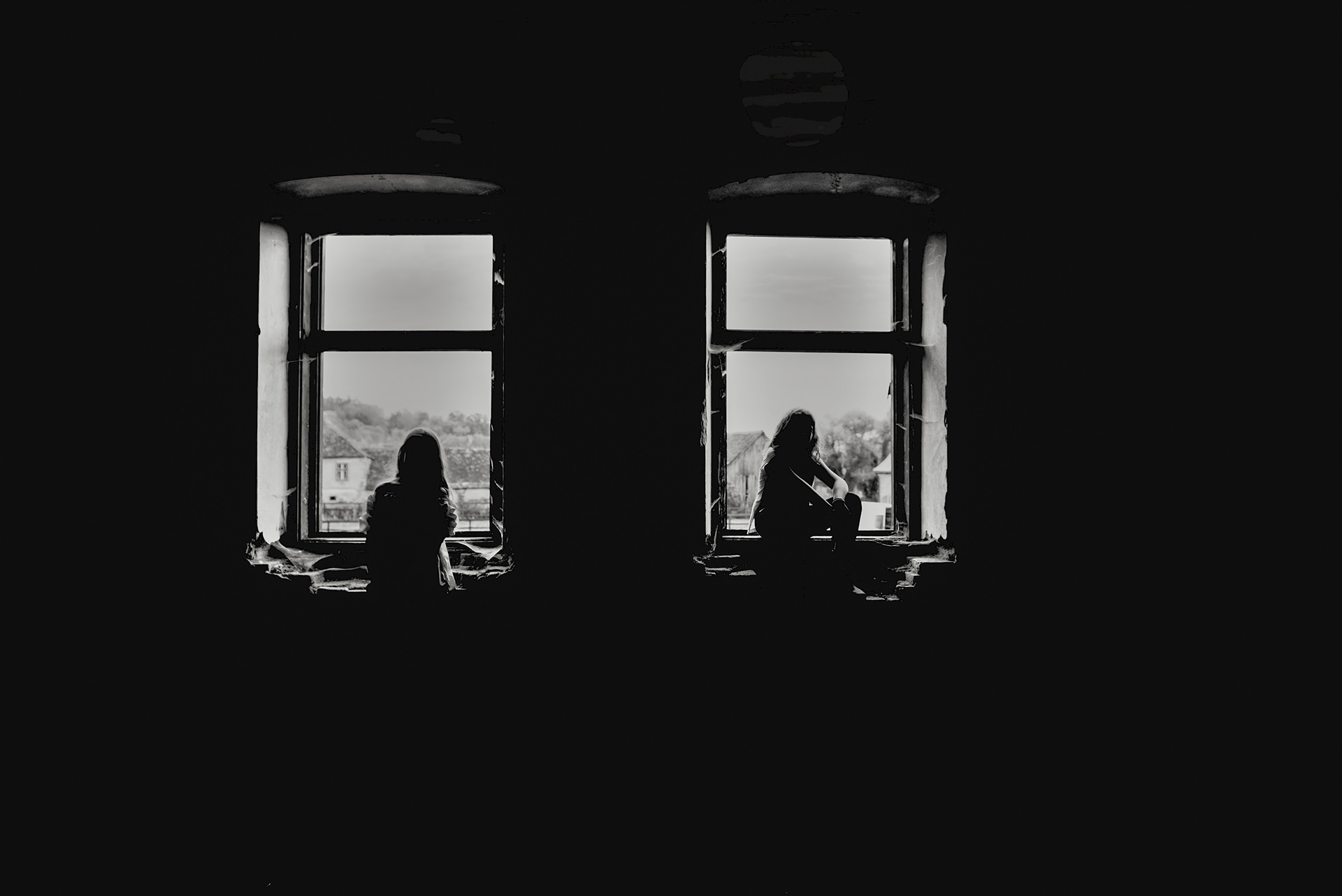 two figures visible through village house windows