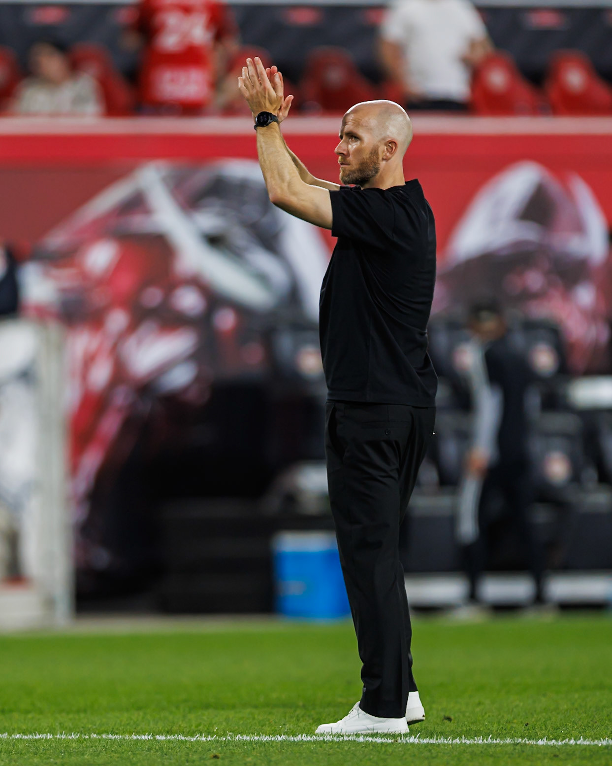 New York Red Bulls head coach Michael Bradley applauds the supporters.