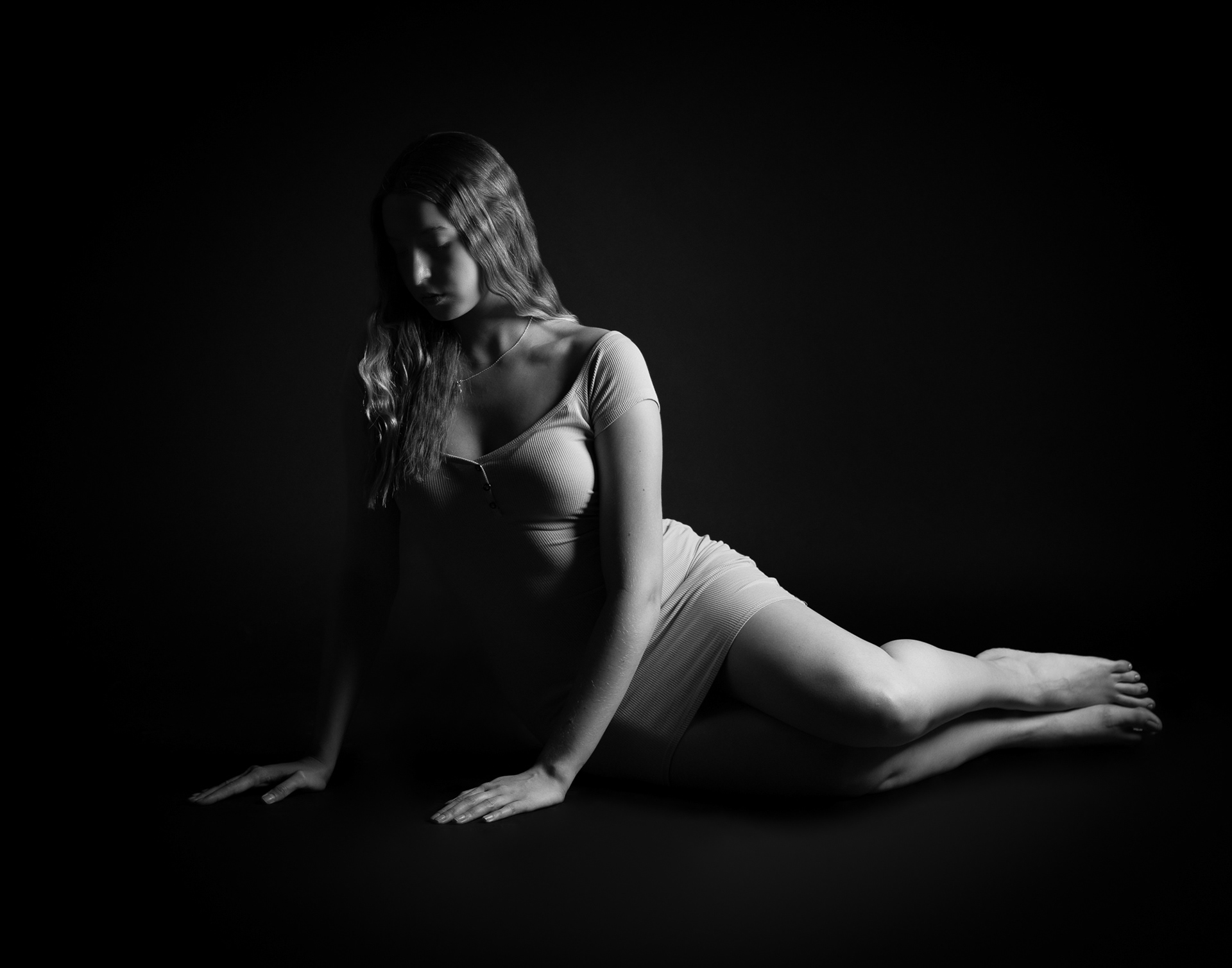 Artistic black and white photo of woman posing in a dress on the floor