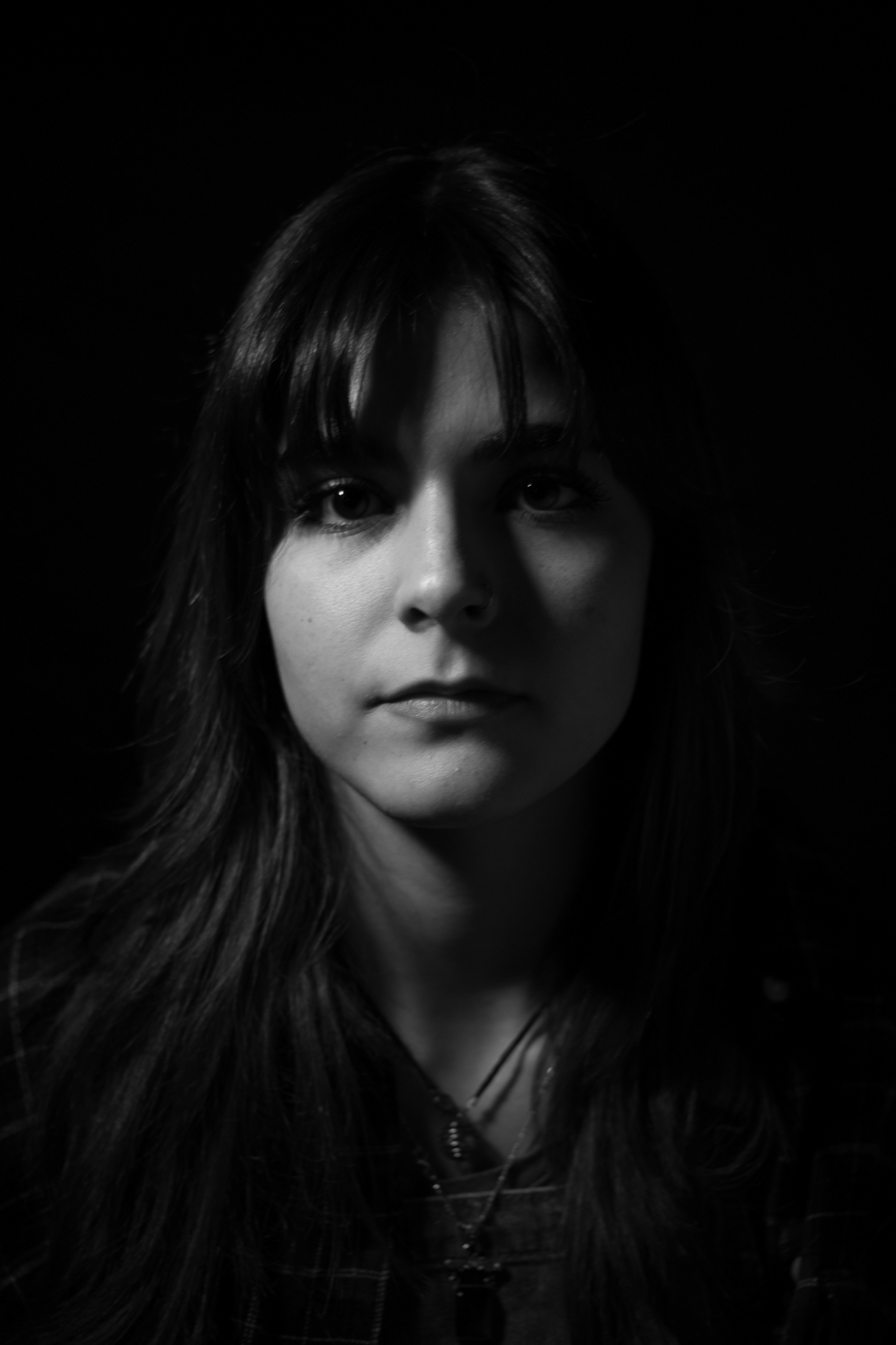 Black and white rembrandt portrait of a woman looking directly into the camera