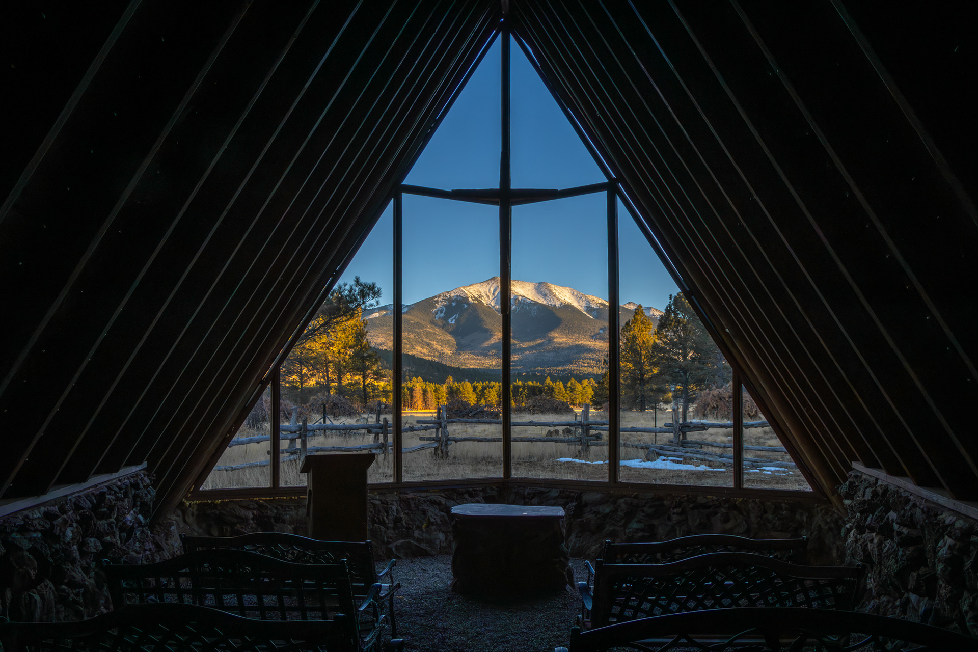 Cozy cathedral interior with panoramic window view of snow-capped peaks