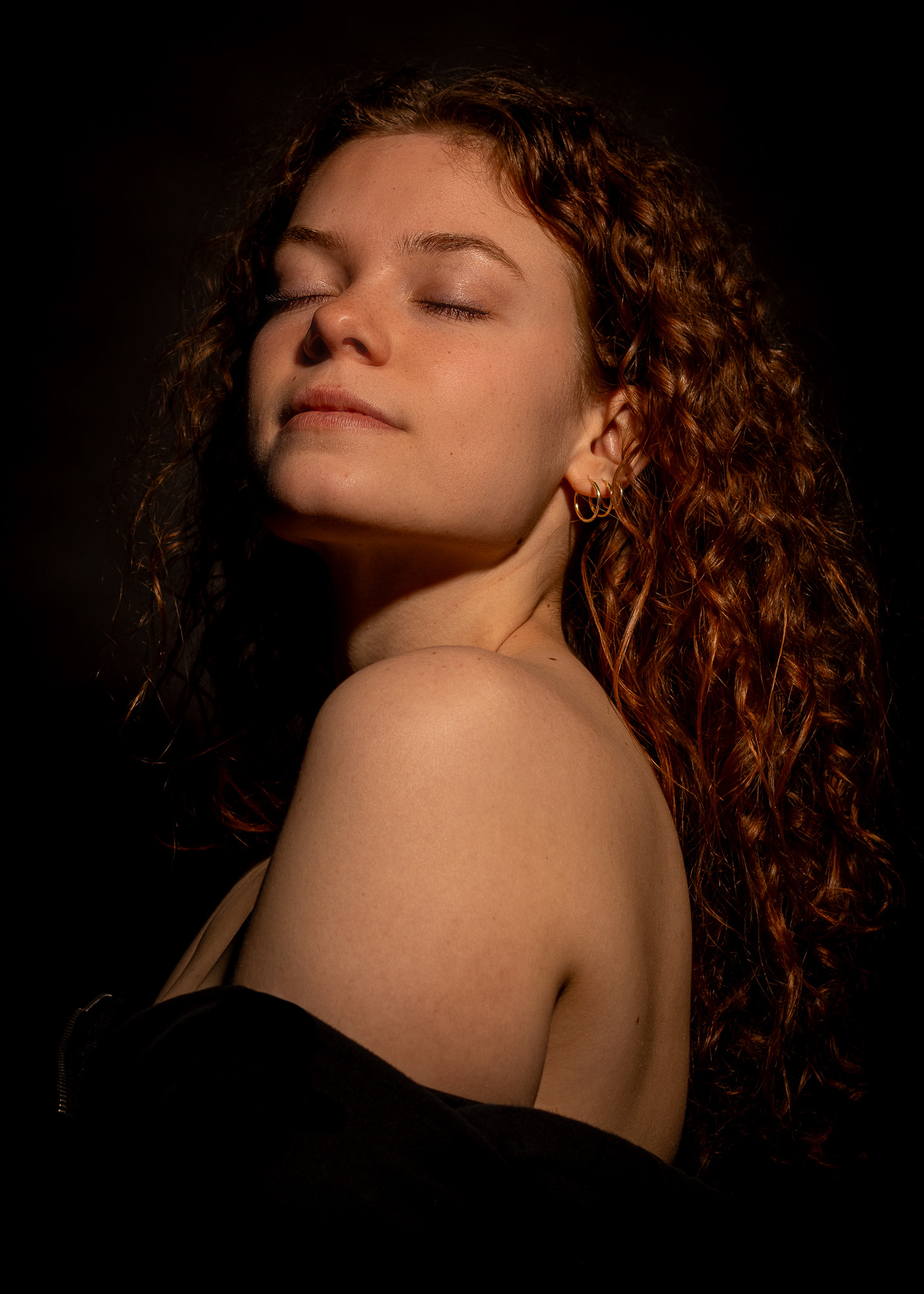 Dramatic portrait of a woman with curly hair in warm, soft light