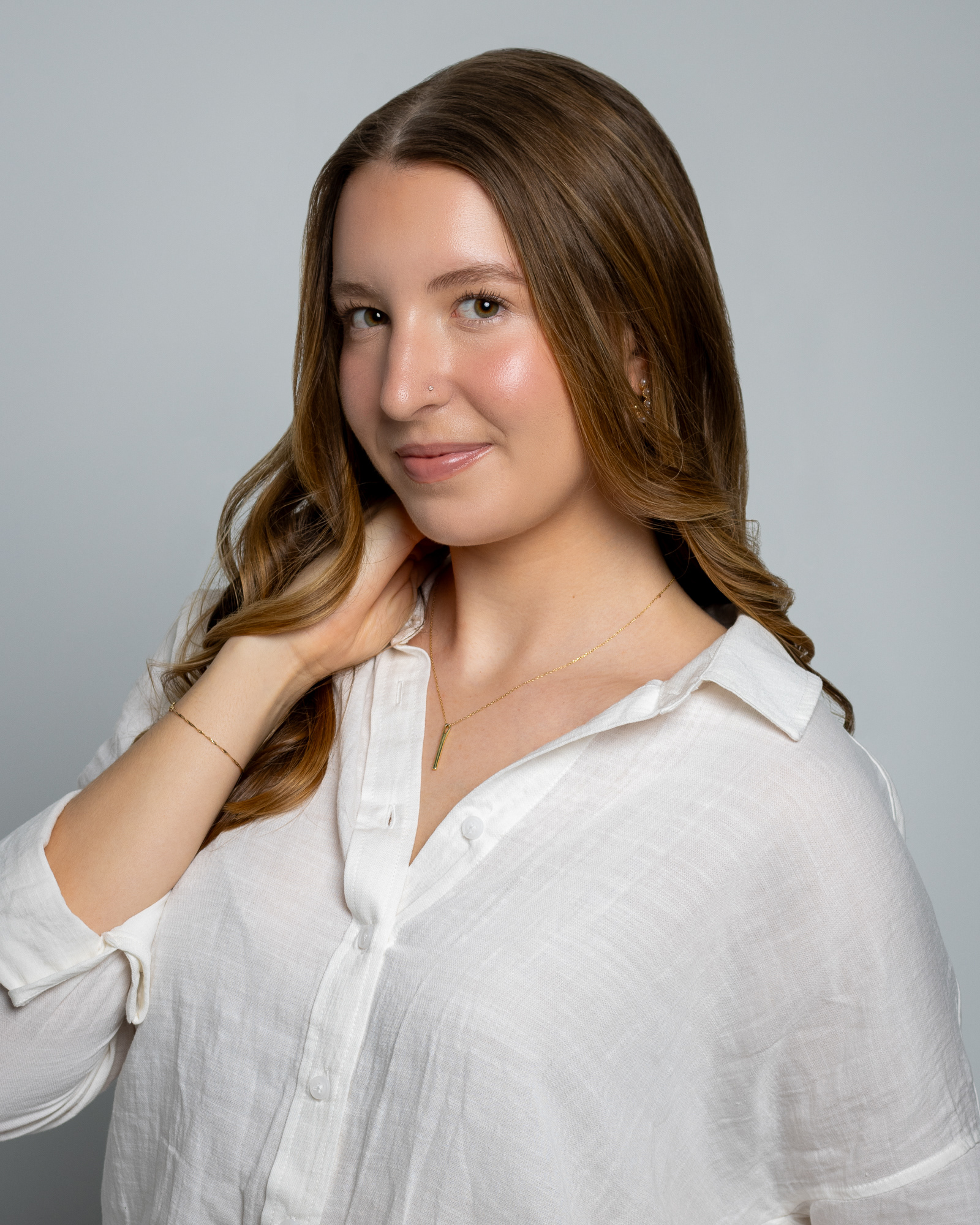 Soft portrait of a woman in white blouse, posing with a gentle smile