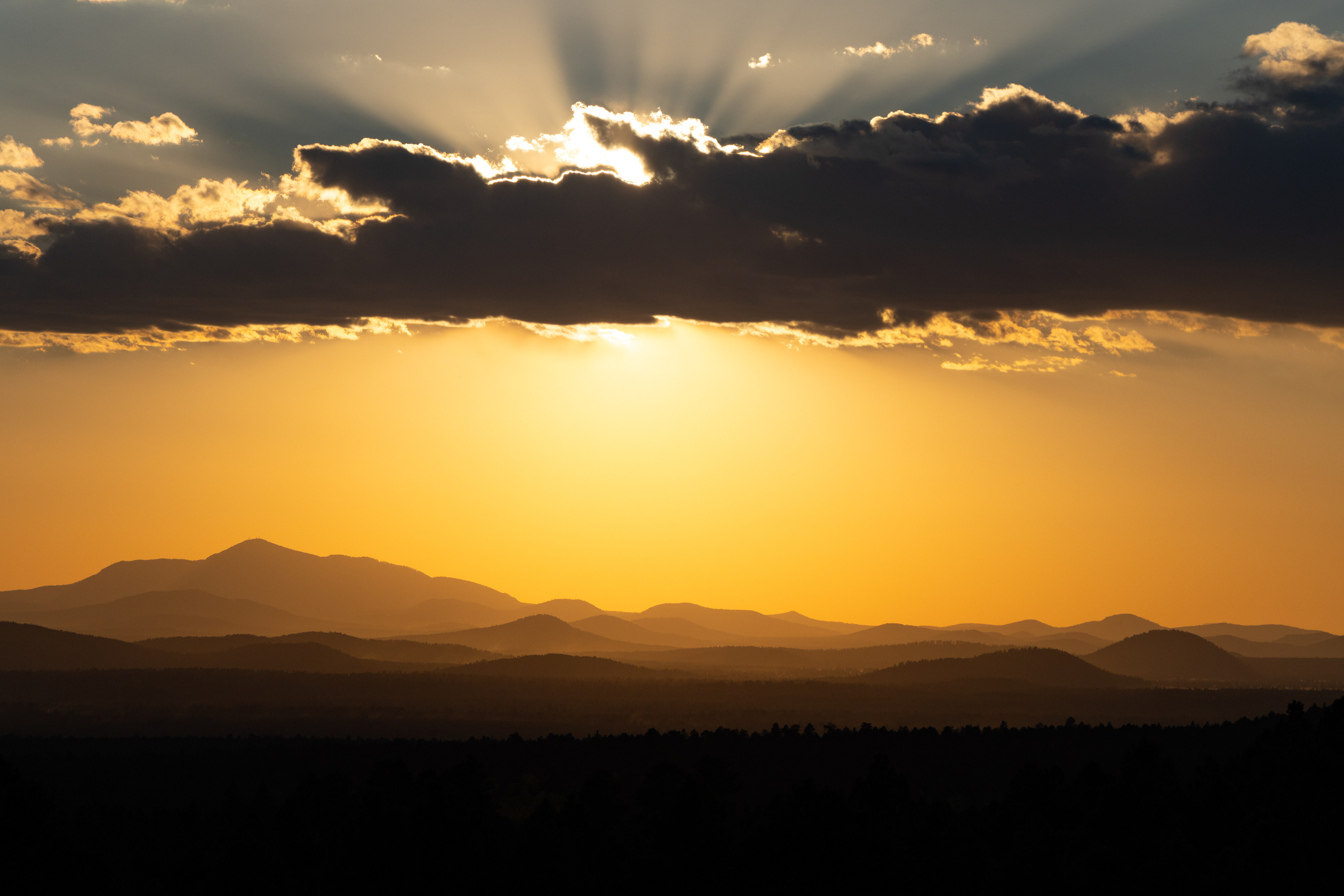Dramatic sunset over mountain silhouettes with sun rays through the clouds