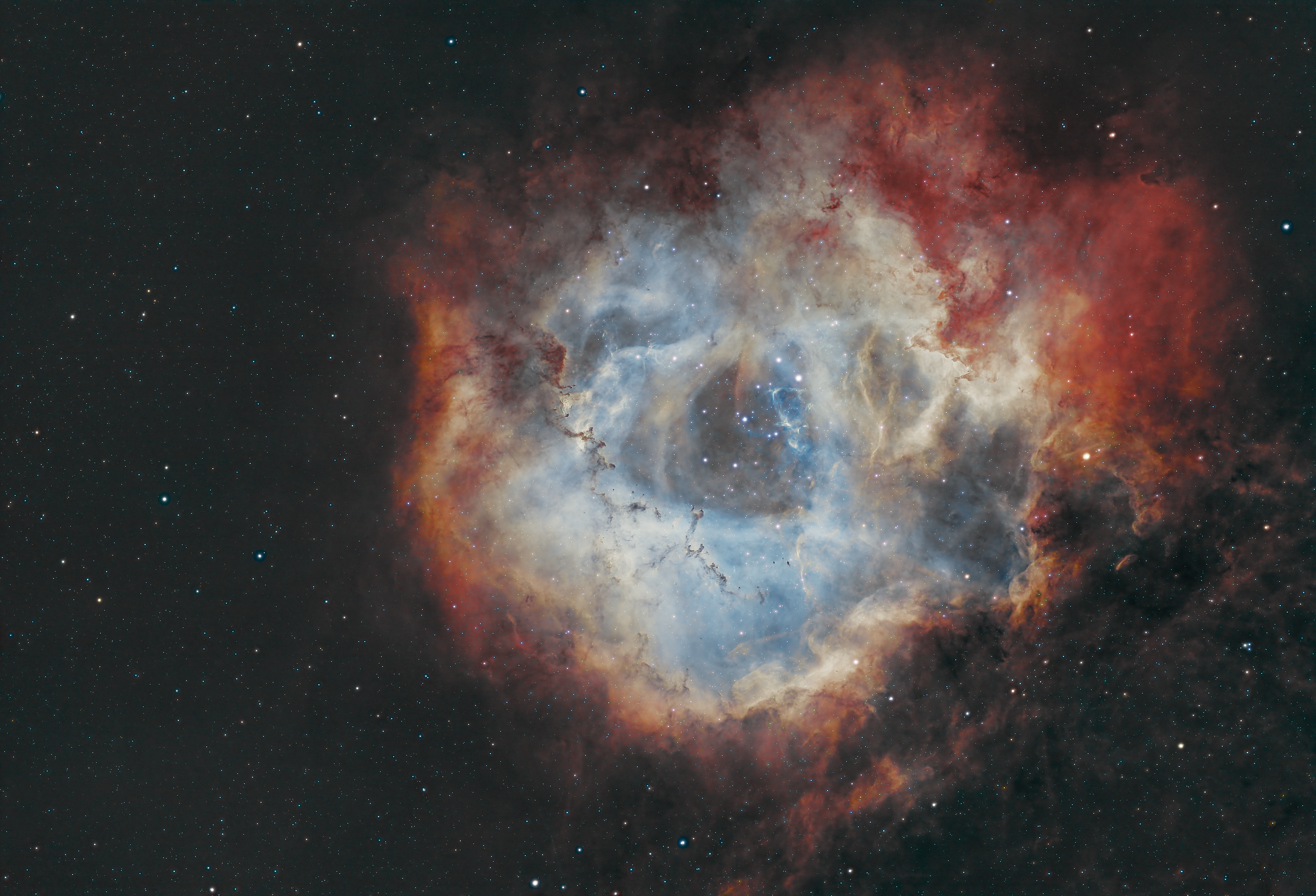 The Rosette Nebula, also known as NGC 2237, is a vast and beautiful emission nebula located about 5,000 light-years away in the constellation Monoceros (the Unicorn). Shaped like a blooming cosmic rose, this nebula spans roughly 130 light-years across and is part of a larger molecular cloud. At its heart lies the open star cluster NGC 2244, whose young, hot stars produce intense ultraviolet radiation that ionizes the surrounding hydrogen gas, causing it to glow with a vibrant red hue. The stellar winds from these stars also carve out the nebula’s central cavity, creating its distinct floral appearance. The Rosette Nebula is not only a visual wonder but also a region of active star formation, showcasing the life cycle of stars from birth to maturity.