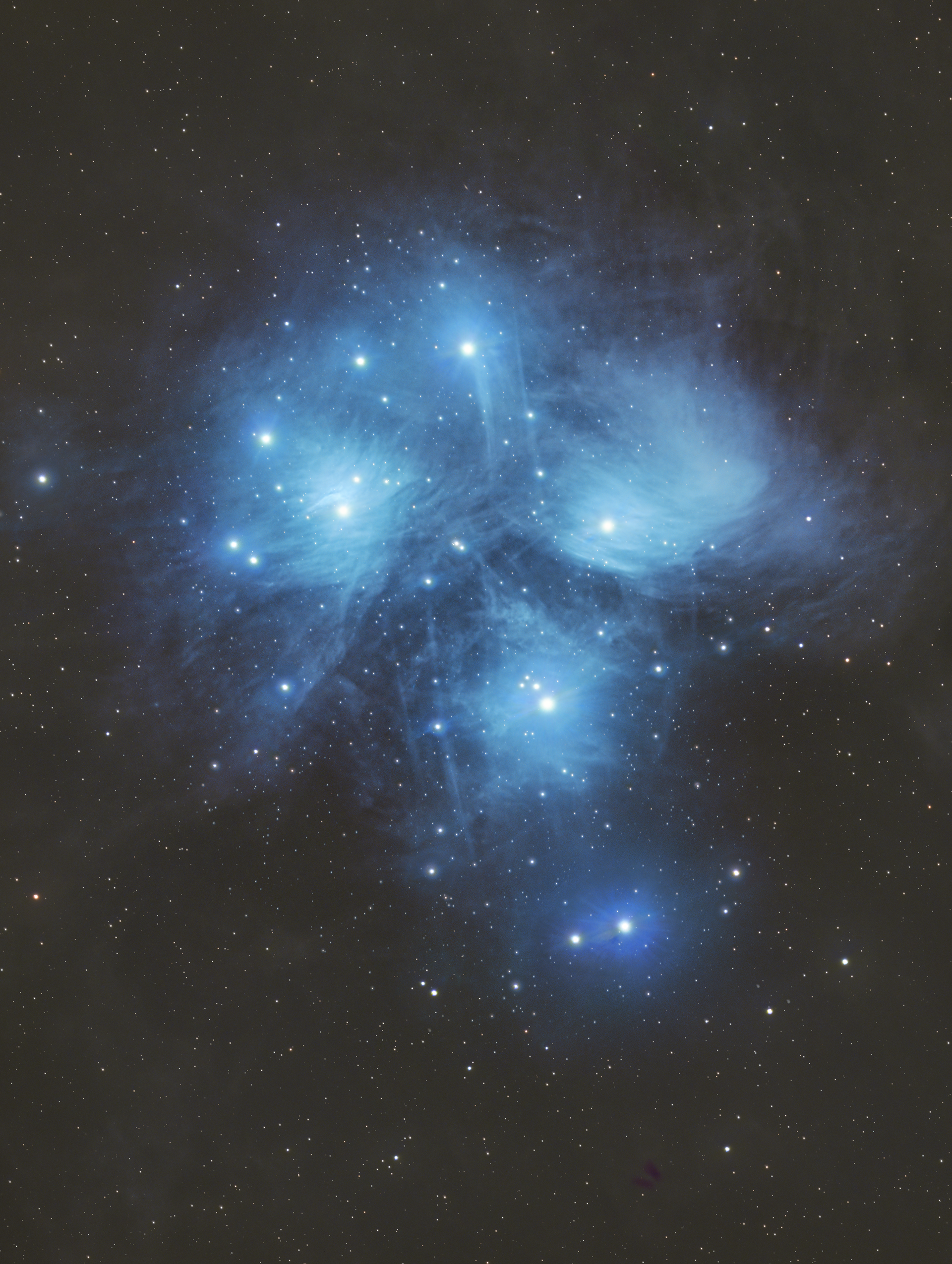 The Pleiades, also known as the Seven Sisters or Messier 45 (M45), is one of the most recognizable open star clusters in the night sky. Located approximately 440 light-years away in the constellation Taurus, the cluster features hundreds of stars, with its brightest members—Alcyone, Maia, Electra, Taygeta, Merope, Celaeno, and Sterope—forming the iconic “Seven Sisters” visible to the naked eye. The Pleiades are enveloped by a reflection nebula, where blue dust clouds shimmer as they reflect the light from the hot, young stars. Revered in cultures and mythologies worldwide, the Pleiades have guided harvests, inspired stories, and remain a beloved target for astronomers and stargazers alike.