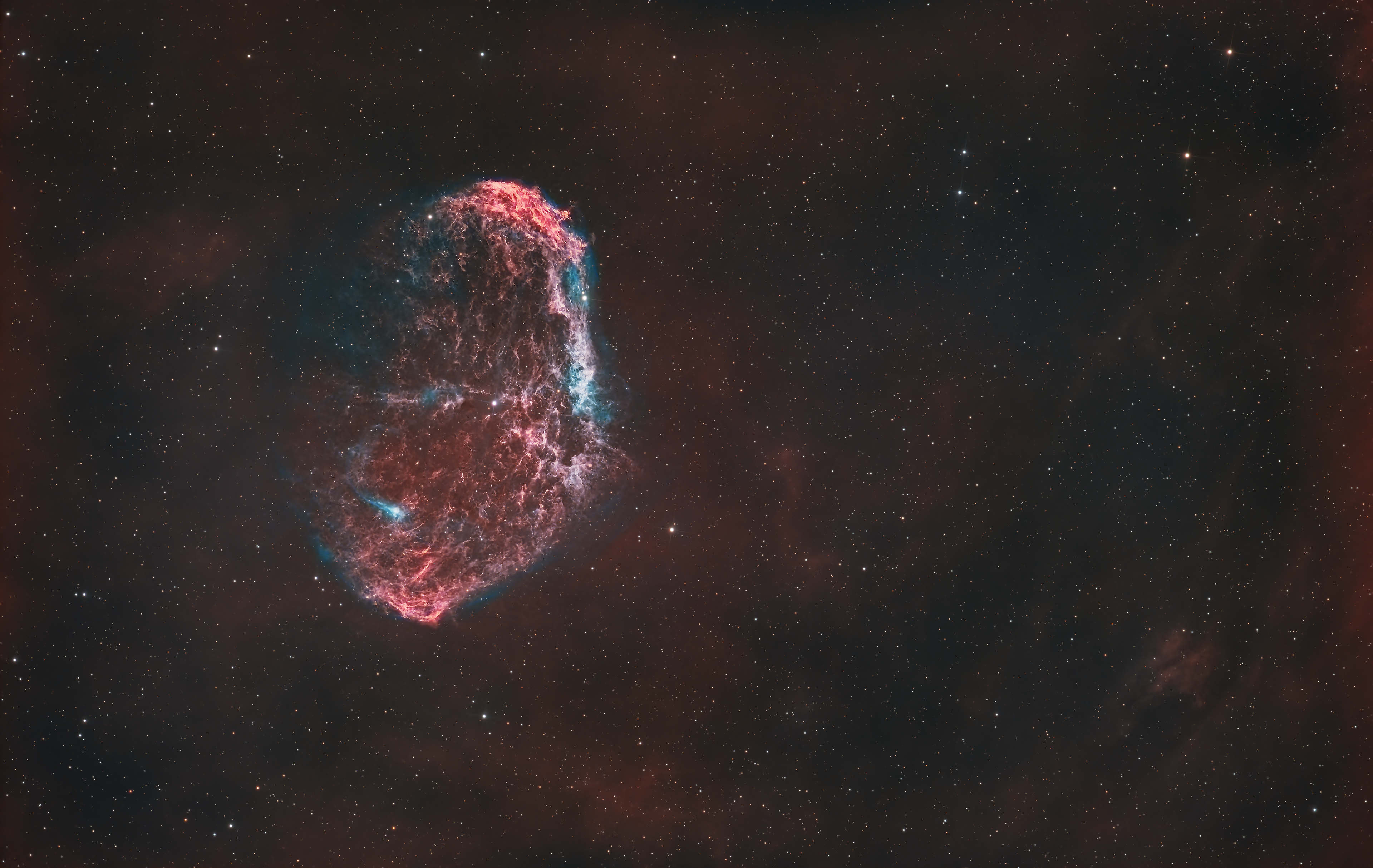 The Crescent Nebula, also known as NGC 6888, is a striking emission nebula located about 5,000 light-years away in the constellation Cygnus (the Swan). It was formed by the powerful stellar winds from the Wolf-Rayet star WR 136, a massive, hot star nearing the end of its life. These winds collide with material ejected during the star’s red giant phase, creating a shell of gas that glows as it is ionized by the intense ultraviolet radiation from the central star. The nebula’s delicate, arc-shaped structures and filaments of hydrogen and oxygen give it a crescent-like appearance, making it a fascinating object for studying the complex interactions of stellar winds and the lifecycle of massive stars.