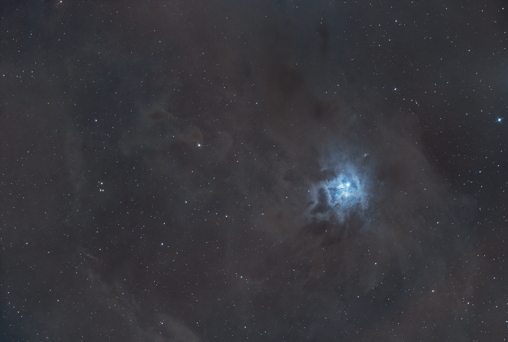 The Iris Nebula, also known as NGC 7023, is a stunning reflection nebula located approximately 1,300 light-years away in the constellation Cepheus. Illuminated by the young, hot star SAO 19158, its soft, bluish glow arises as starlight reflects off surrounding dust clouds. The nebula’s intricate structures create a petal-like appearance, evoking the beauty of an iris flower, which inspired its name. The Iris Nebula not only captivates with its visual appeal but also serves as a fascinating stellar nursery, offering insights into the early stages of star formation and the interaction between light and interstellar dust.