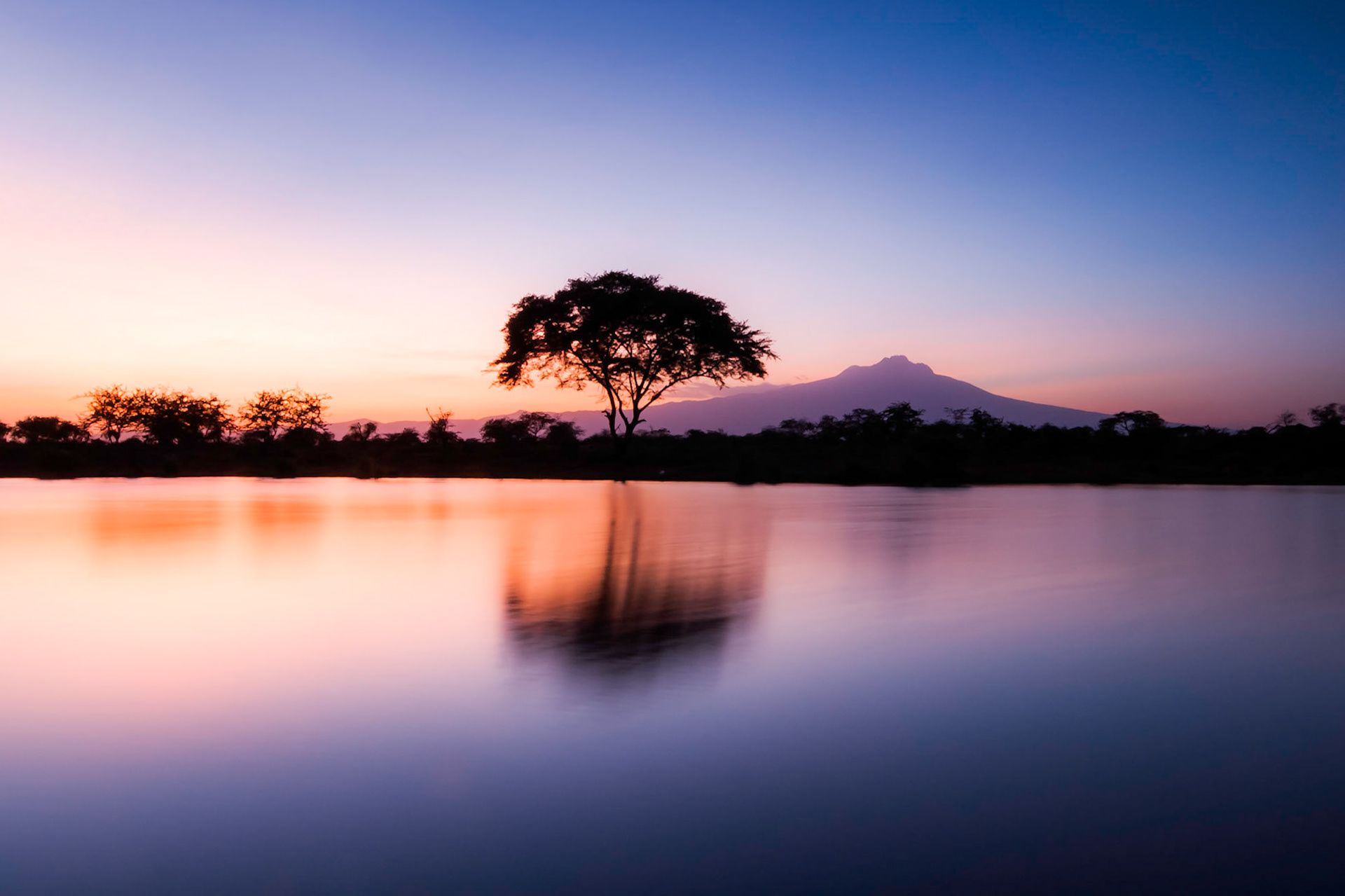 Voyager LodgeZuwani EstateTsavo West National ParkKenyaThis is easily one of my top locations in Kenya, and one location that I have revisited over ten times. Each time I have photographed this same scene, from various positions and compositions. The foreground is a watering hole, full of Crocodiles and Hippos. In the back drop, standing proud, is Mt Kilimanjaro. Easily my favourite sunset in Southern Kenya.This shot was on about my eigth visit to this location. For once I actually had my tripod with me. Captured with a 15 sec exposure and a ND4 Grad Filter.