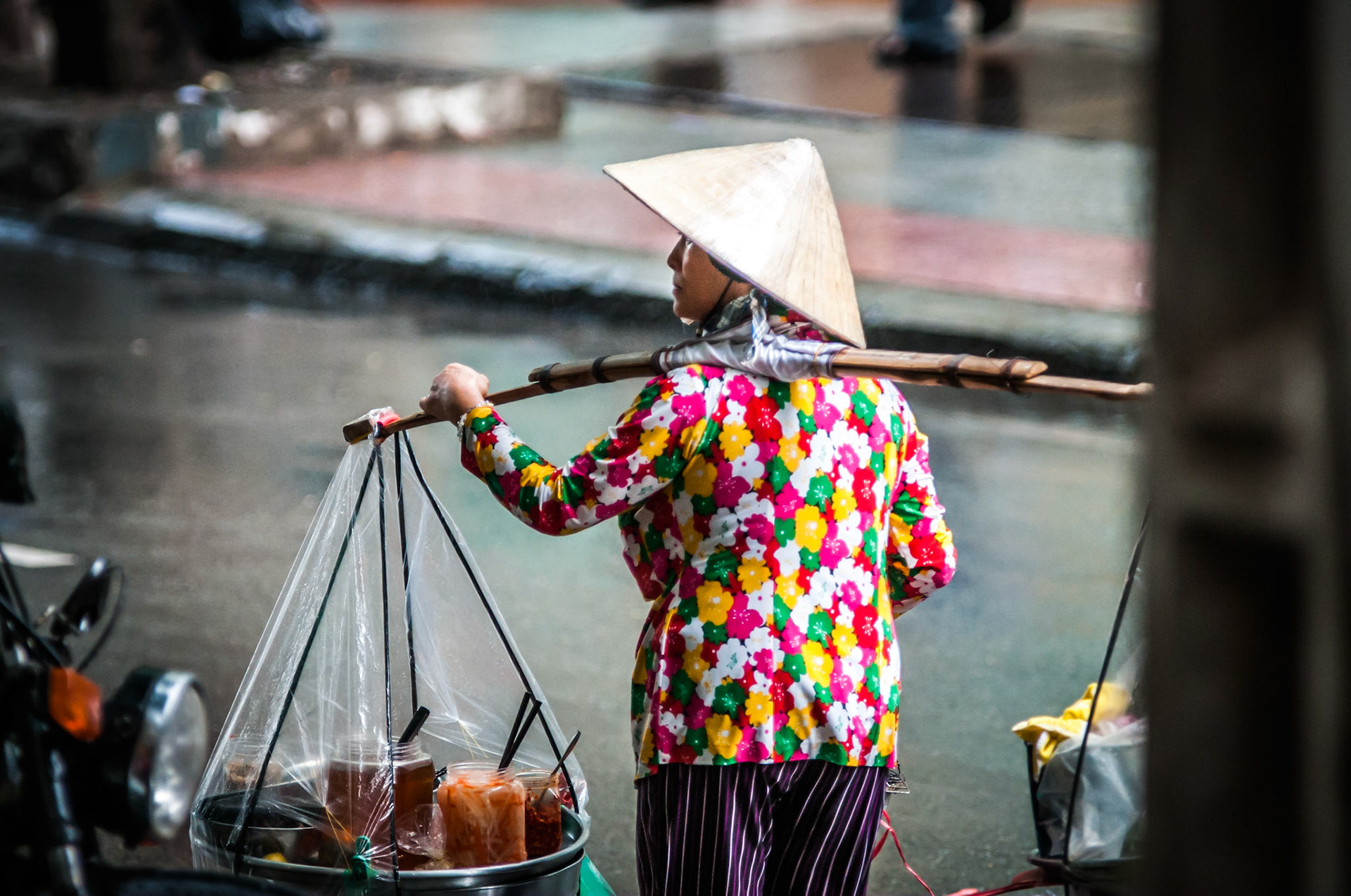 A street vender walks the monsoon drenched streets of Hanoi searching for hungry customers. A rather candid shot taken from the shelter of a nearby cafe. Not by far my cleanest or sharpest image but I feel it best suits the atmosphere, feel and character that encapsulates the bustling oriental streets of Hanoi.