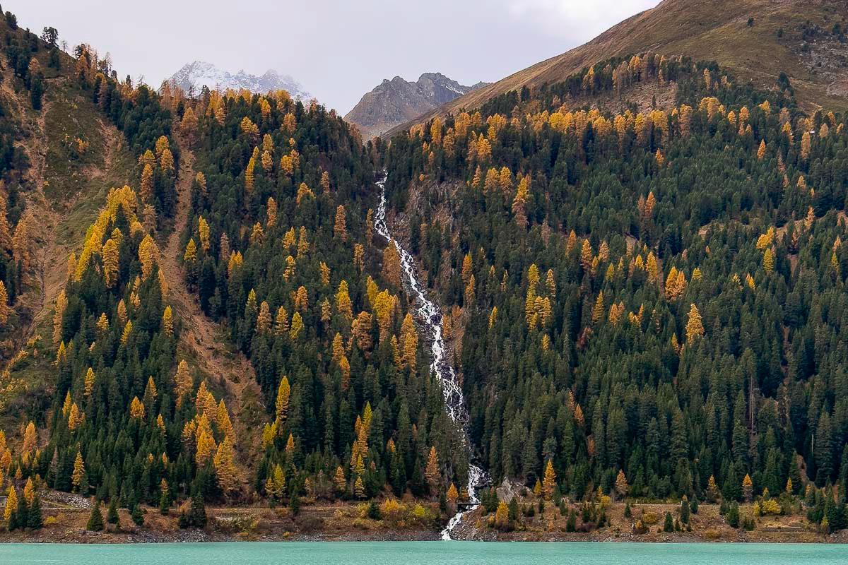 overview of a waterfall coming from the mountains and flowing into the mountain lake