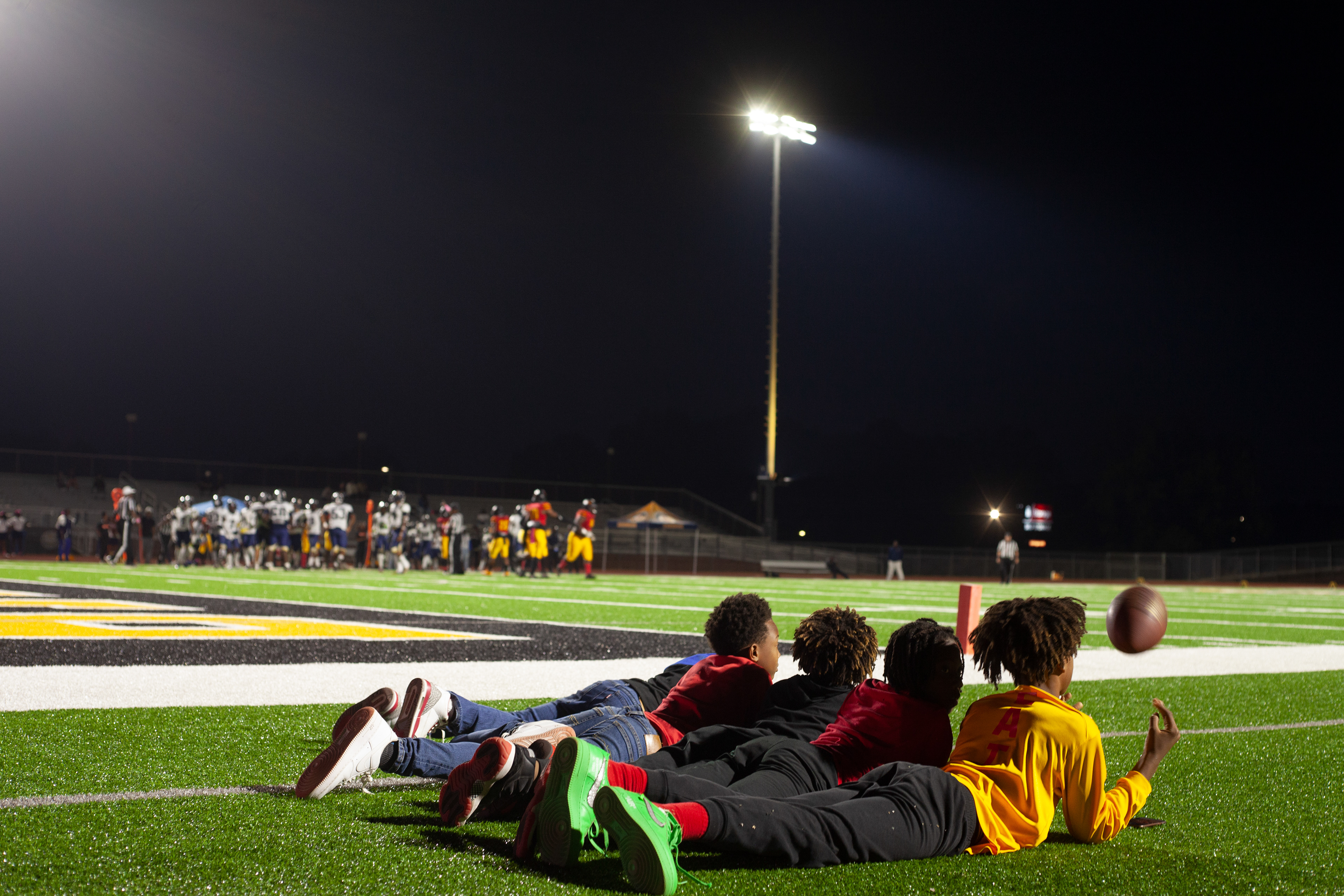 Five young kids lay on the sidelines of the Northeast vs. Kendrick highschool football game at Ed Defore Sports Complex on Oct. 7, 2022. It is Northeast High School's homecoming game, which they won 49-16. 