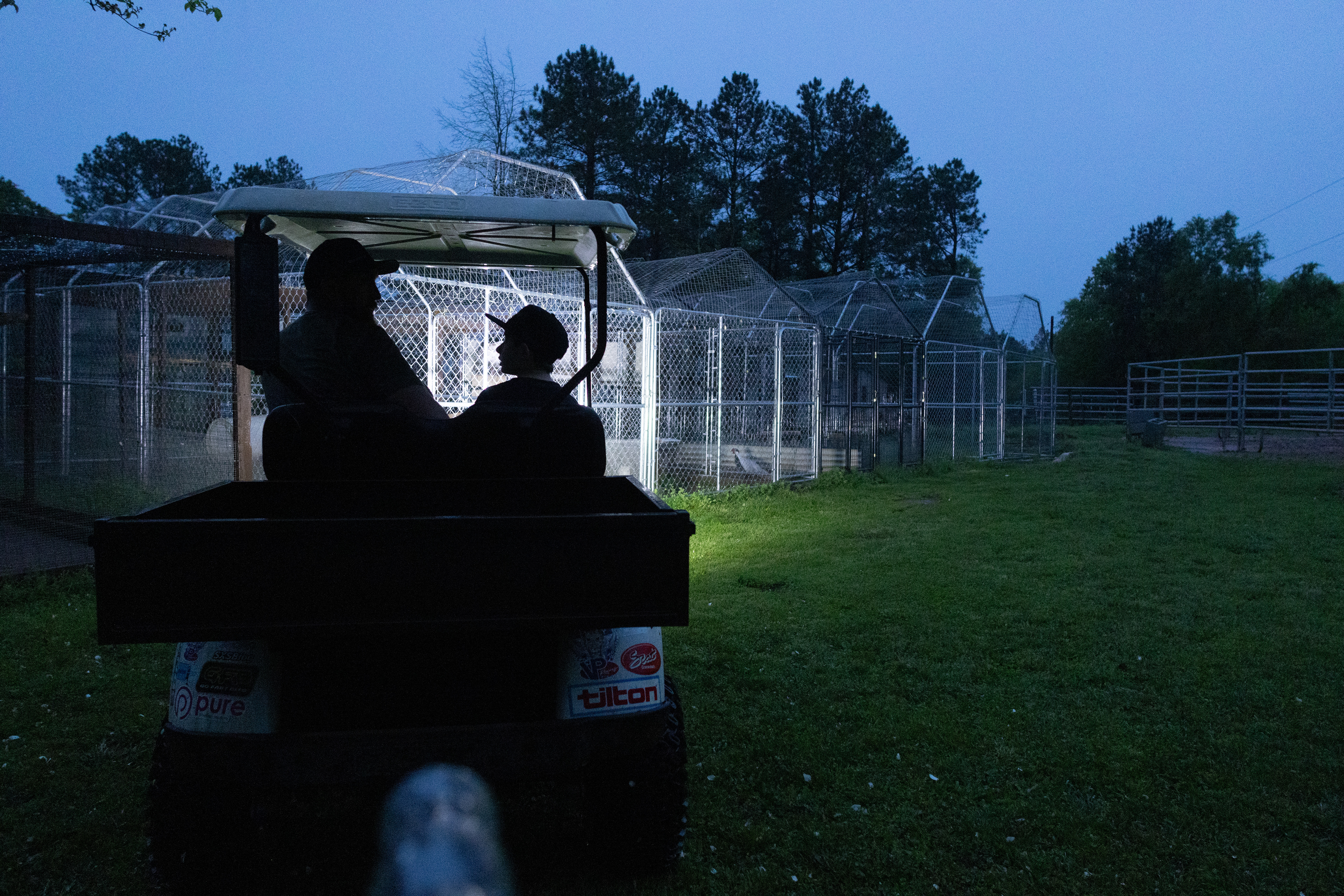 Mason Campbell, 8, and his father Brian Campbell sit in the family's golf cart and share a conversation as they check on the small farm located in the backyard of their house in Carlton, Ga on April 6, 2025.