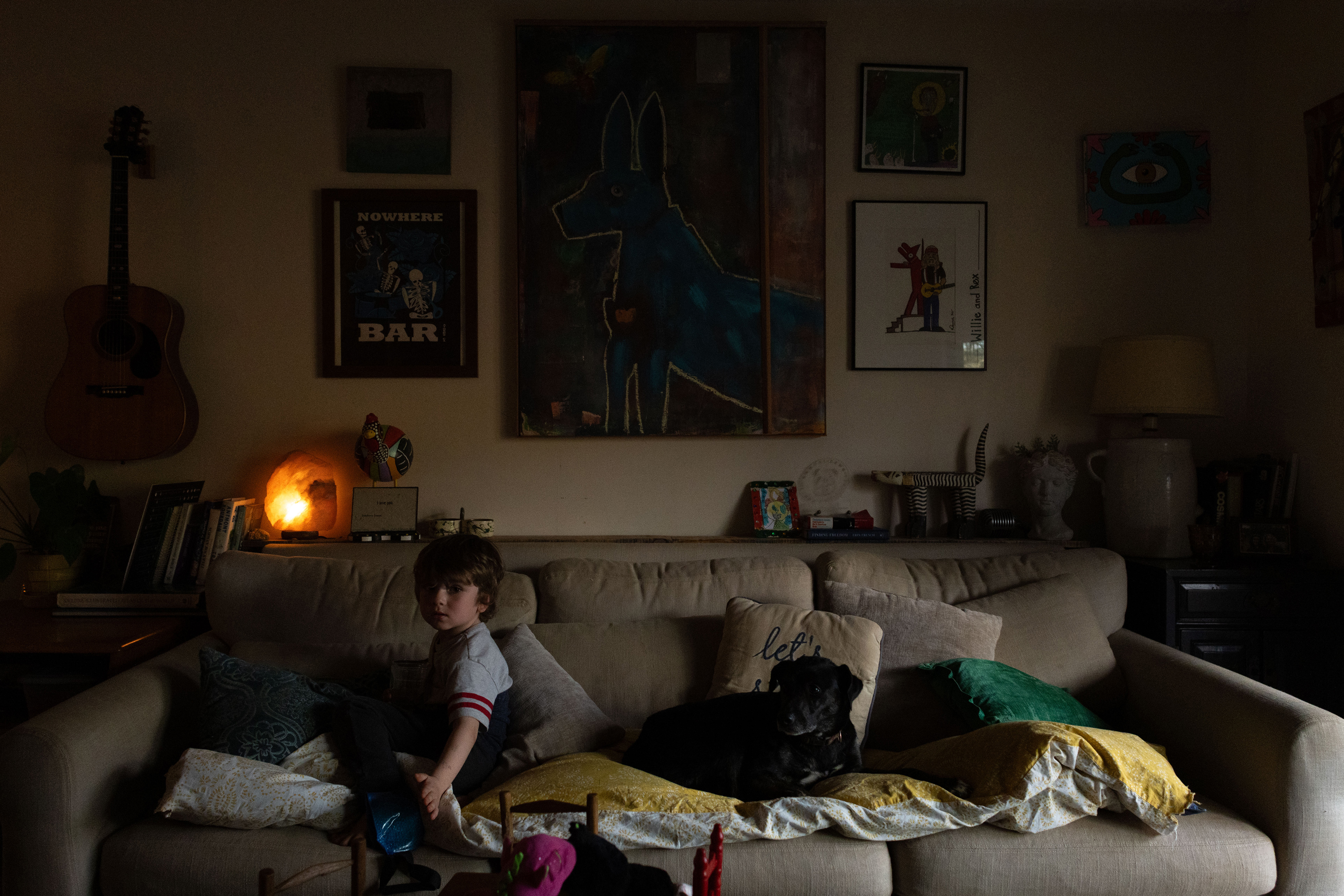 Hank O'Day (5), son of Scott Low and Nicole Kelley, ices his ankle on the couch inside of his home in Rabun County, Ga on March 14, 2025, after playing outside. One of the family's dogs, Little Bear, accompanies him. (Photo / Lux Corrona)