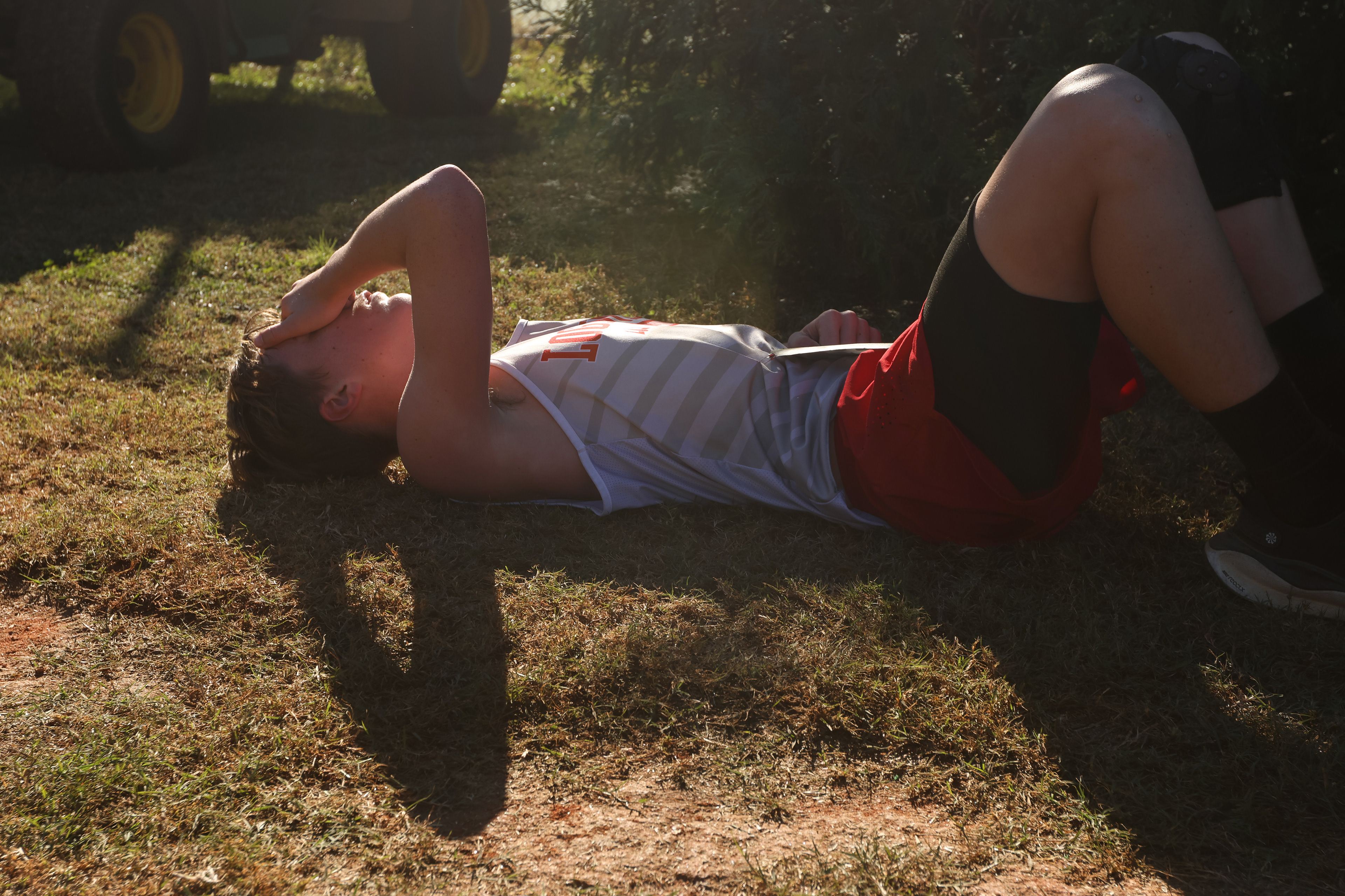 Dylan Crane of Loganville high school lays in the grass to catch his breath moments after finishing in the Men's JV Championship race at the North Oconee Cross Country Invitational on Oct. 19, 2024.