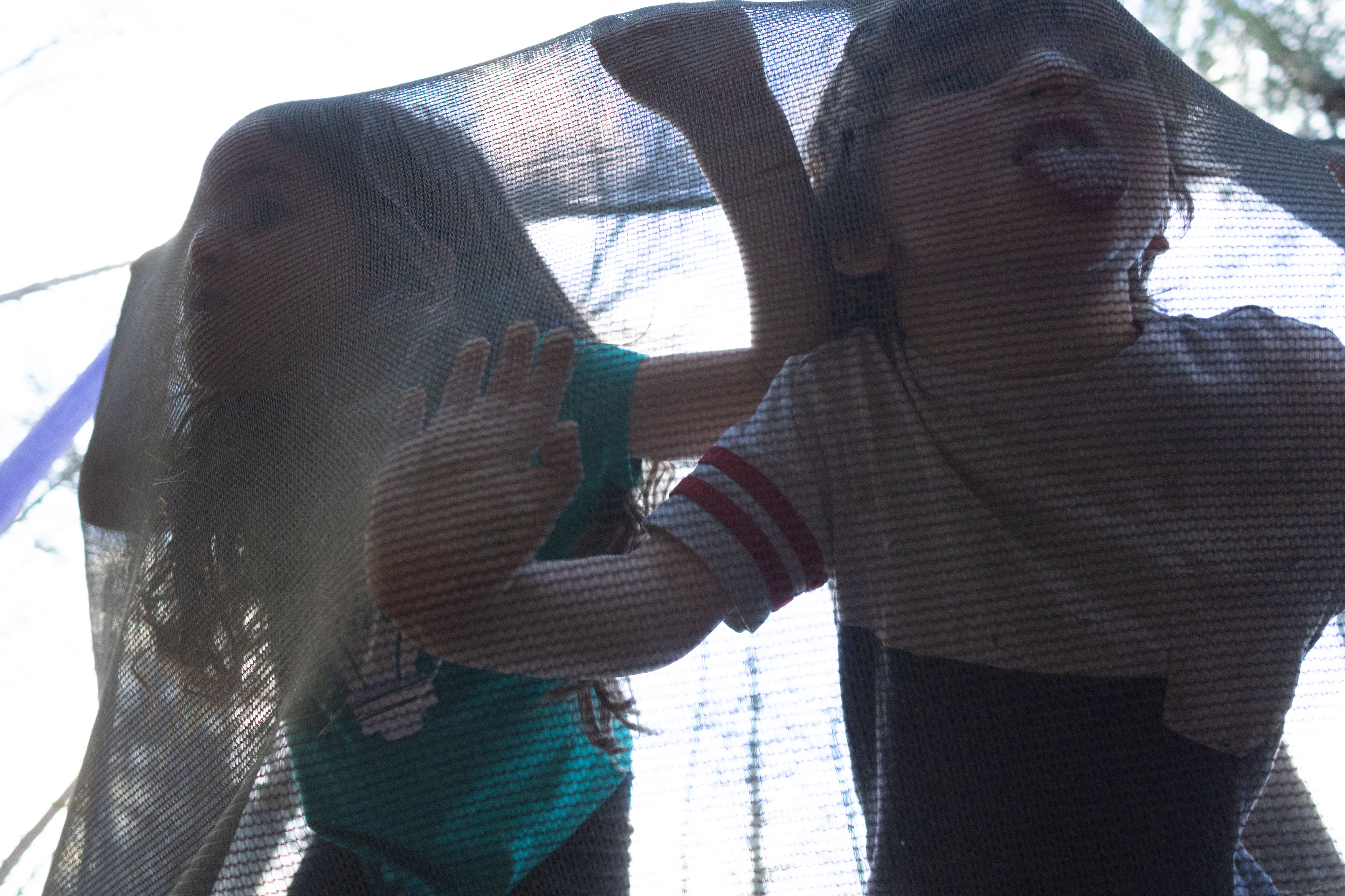 Winnie O'Day (8) and Hank O'Day (5) press their faces against the trampoline in their family's backyard in Rabun County, Ga on March 14, 2025.  