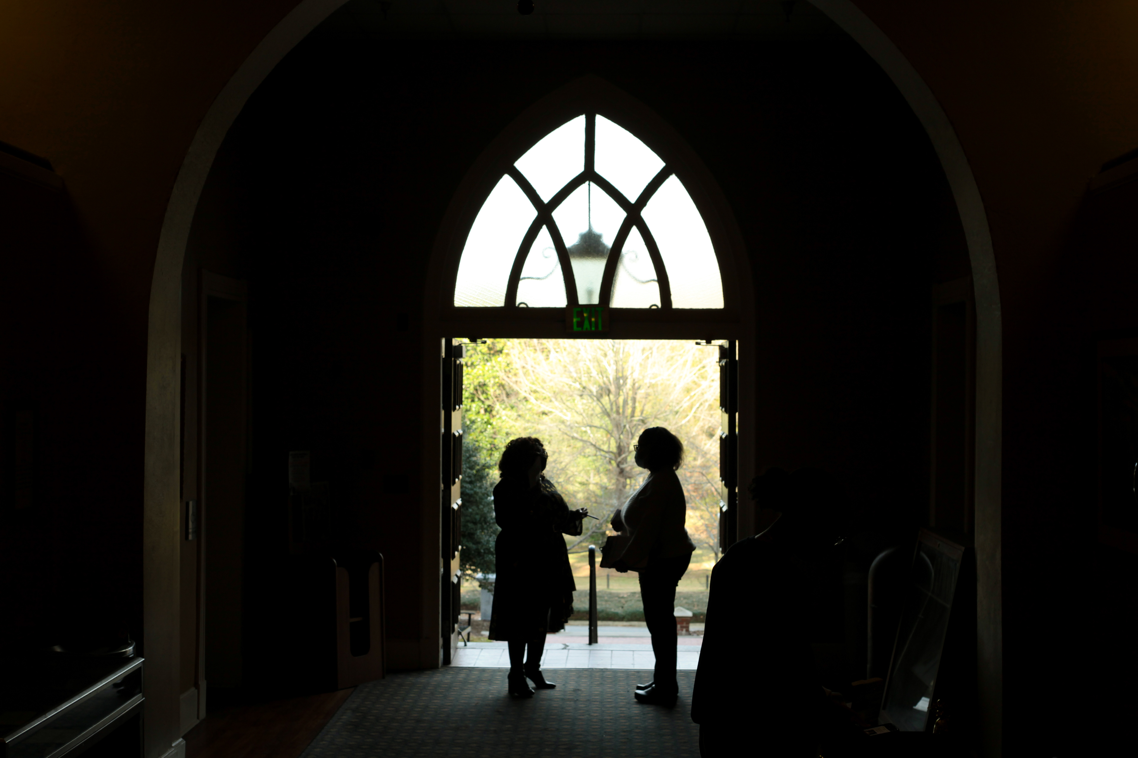 Two faculty members talk as they welcome students, faculty, and staff inside Willingham Auditorium to honor Martin Luther King Jr. on Jan. 13, 2022.