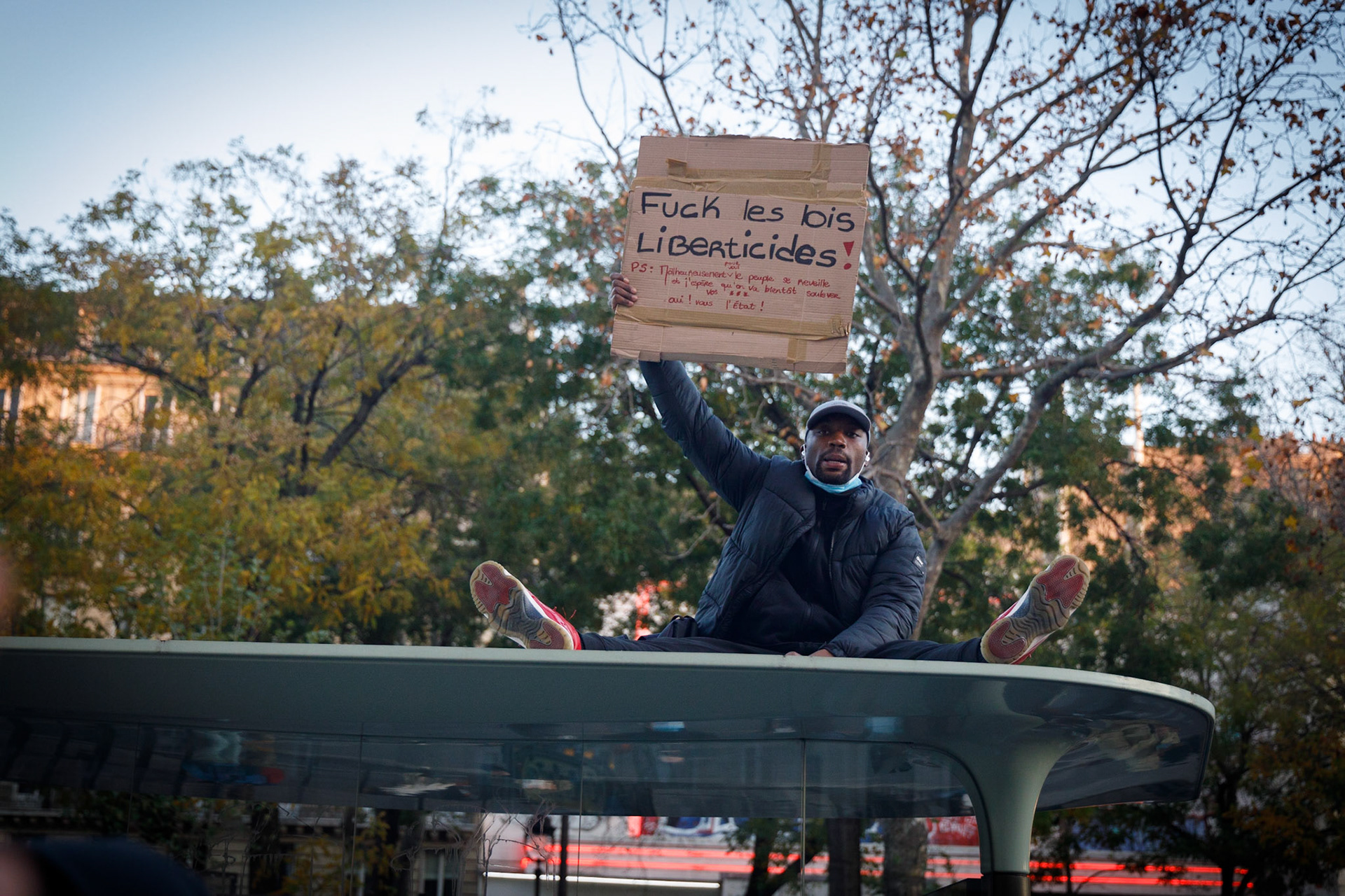 Un manifestant, assis sur un abribus, portant une pancarte “fuck les lois liberticides”, lors de la marche des libertés à Paris, le 28 novembre 2020. Manifestation contre le projet de loi de sécurité globale et notamment son article 24, à l’appel de syndicats et d’associations de journalistes (SNJ, SNJ-CGT), de réalisateurs, d’organisations de défenses de droits humains…Paris, FRANCE - 28/11/2020