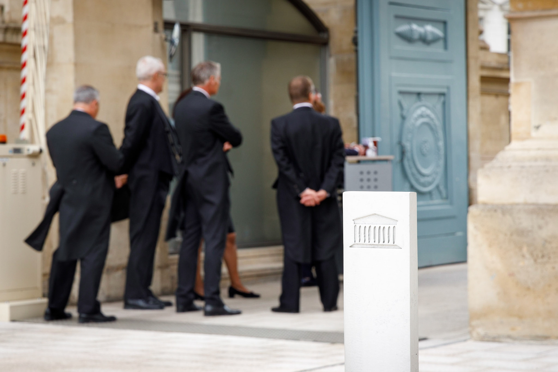 Photo représentant le logo de l’Assemblée nationale sur un poteau avec en arrière plan les huissiers attendant l’arrivée des nouveaux députés à Paris, le 20 juin 2022. France, Paris, 20-06-2022