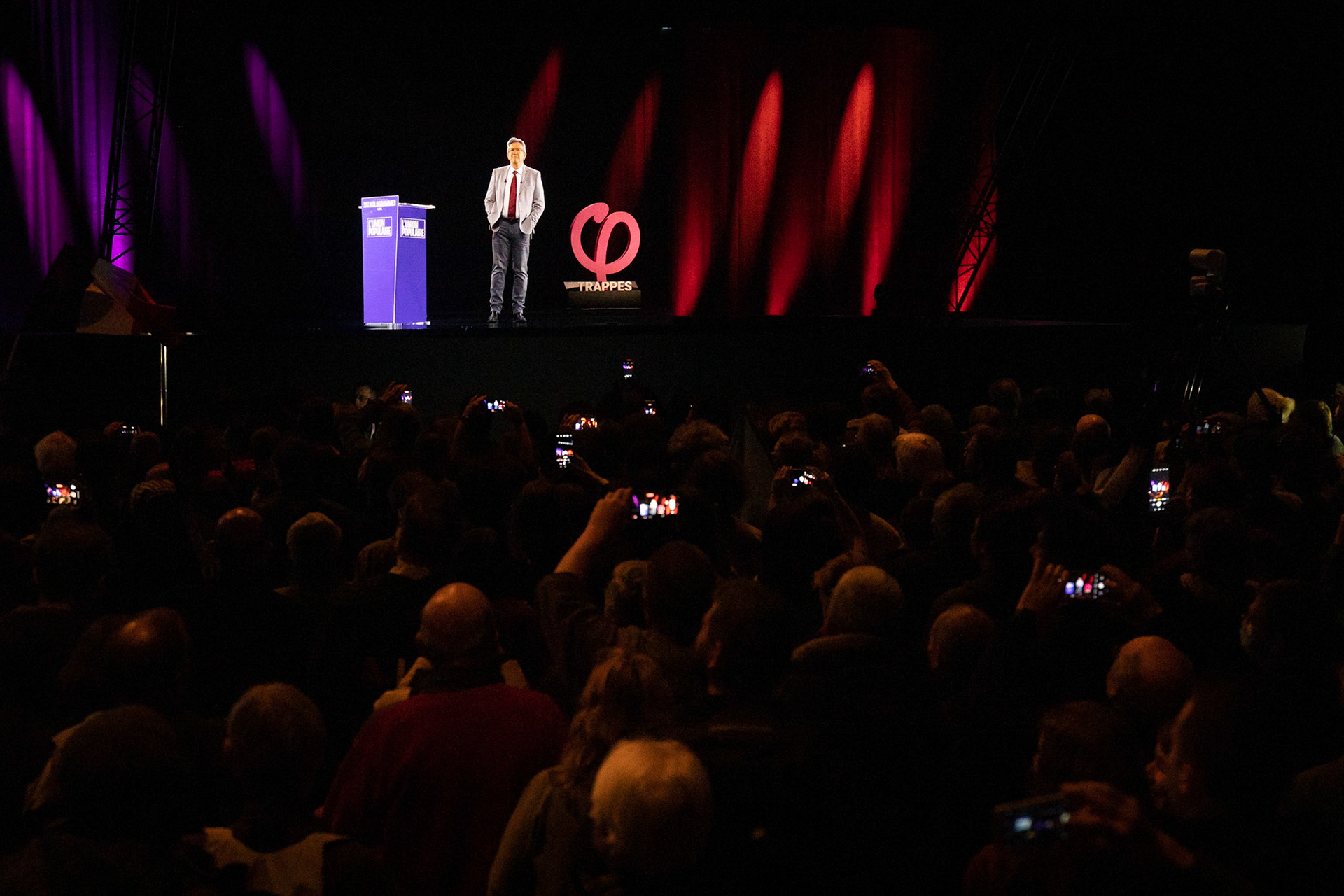 Le public filme l'arrivée, en hologramme, de Jean-Luc Mélenchon sur la scène du théâtre La Merise de Trappes, le 5 avril 2022. Le candidat de la France Insoumise organise un meeting à Lille, retransmis simultanément, en hologramme, dans 11 villes de France, dans le cadre de sa campagne présidentielle.TRAPPES, France - 05/04/2022
