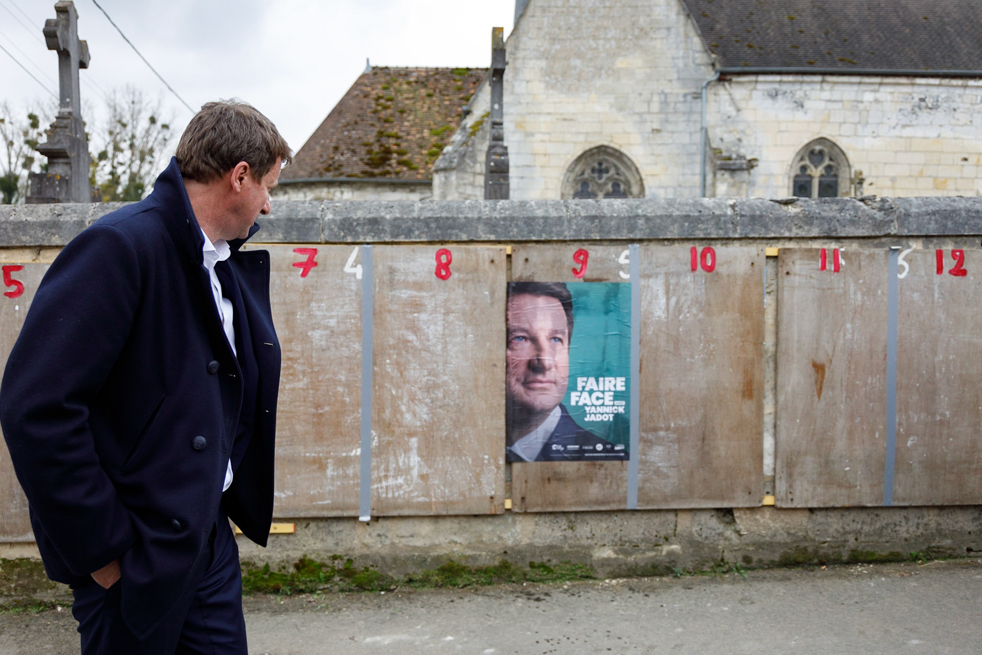 Le candidat écologiste Yannick Jadot passe devant son affiche collée sur les panneaux électoraux du village de Margny-sur-Matz (Oise), le 30 mars 2022. Ce déplacement dans le cadre de la campagne présidentielle a pour thème la ruralité.MARGNY-SUR-MATZ, France - 30/03/2022