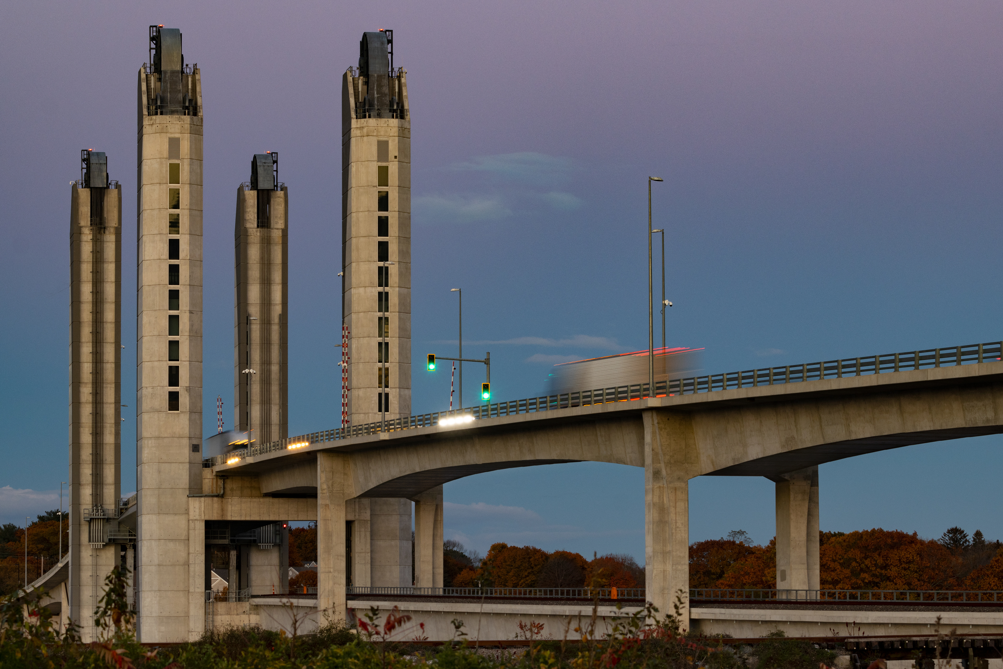 A modern road bridge at dusk with vehicles crossing over as streaks.