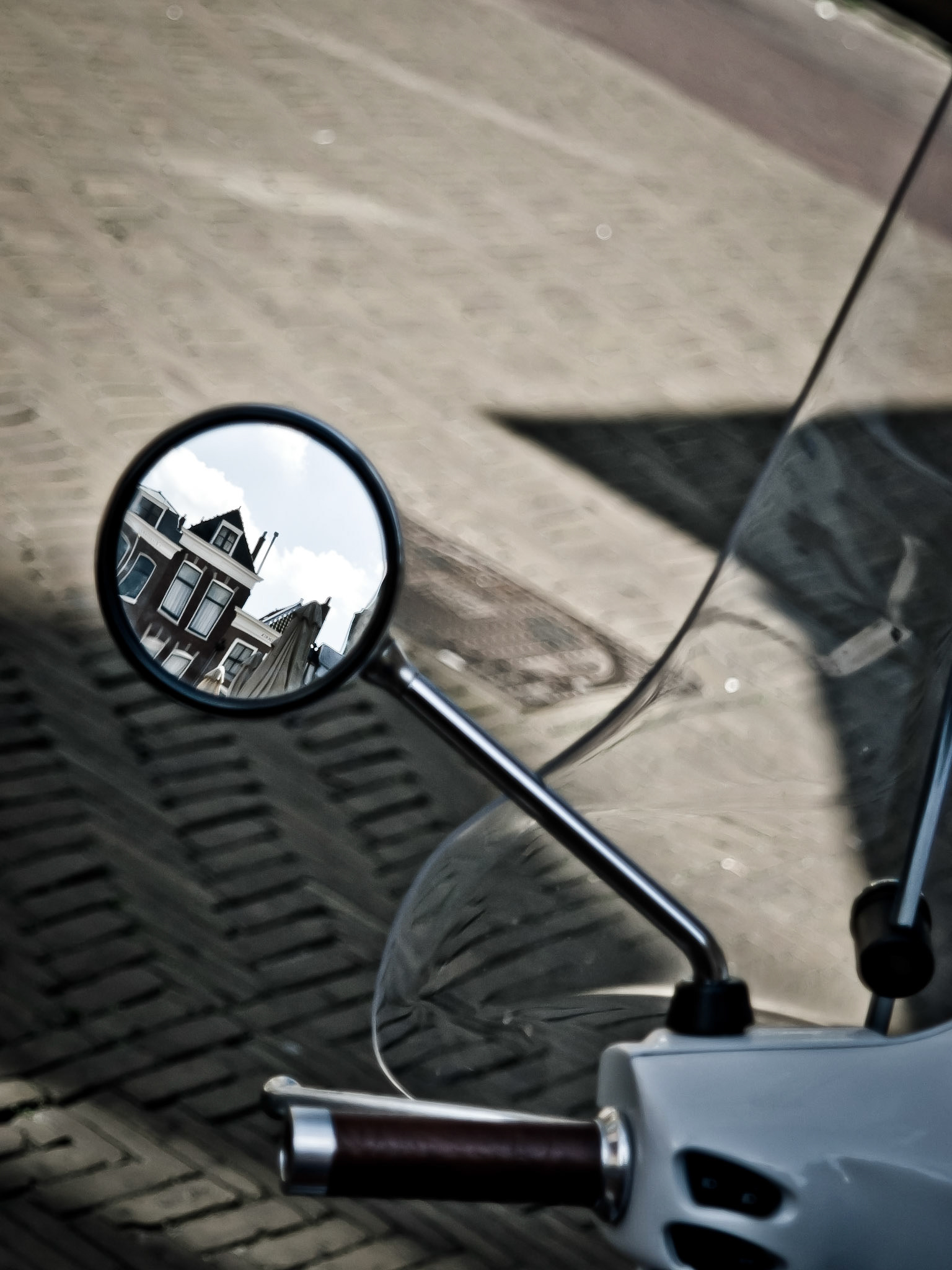 Reflection of typical canal houses in the sideview mirror of a scooter.