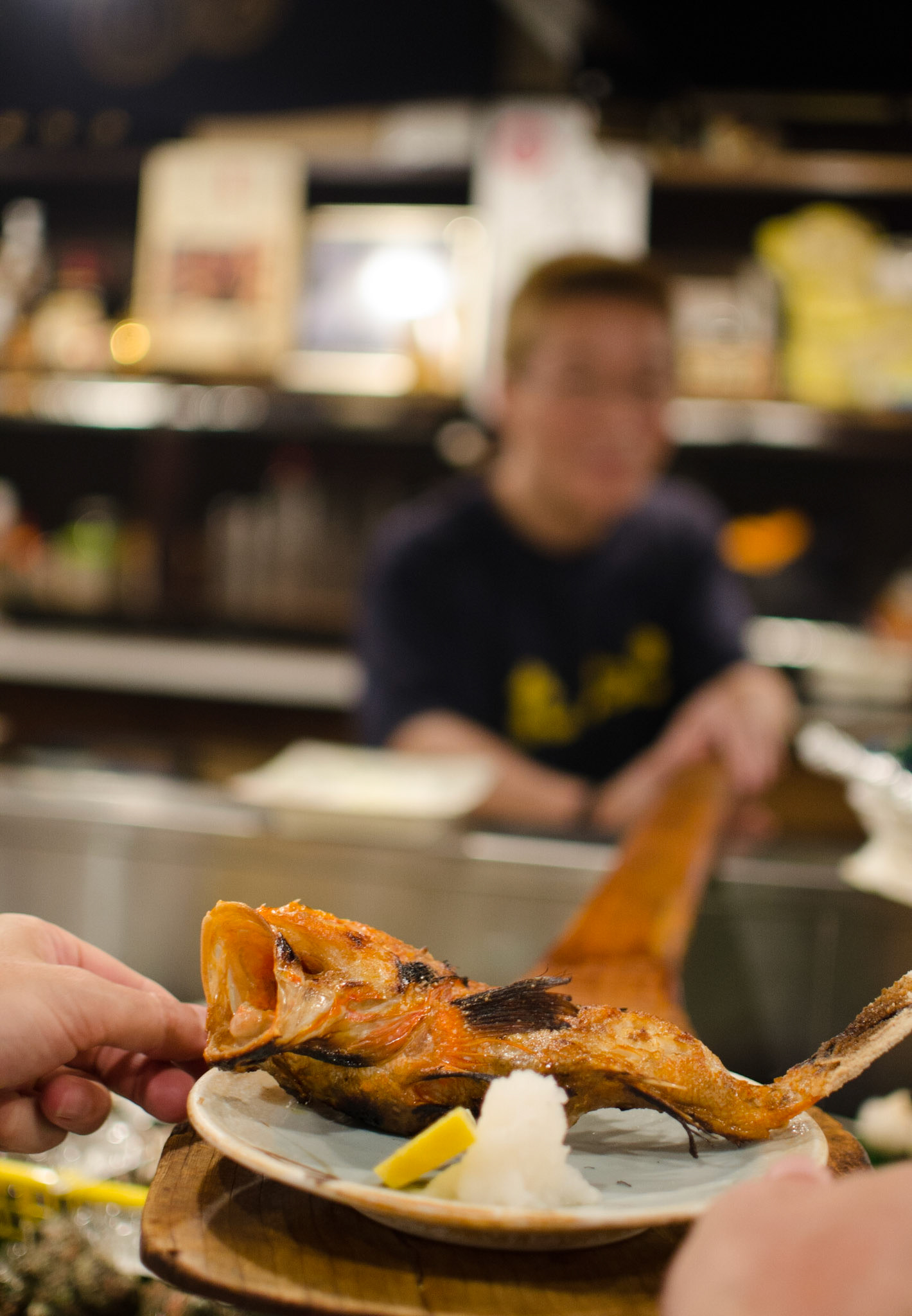 The chef hands us the freshly grilled snapper at a restaurant in Tokyo, Japan.