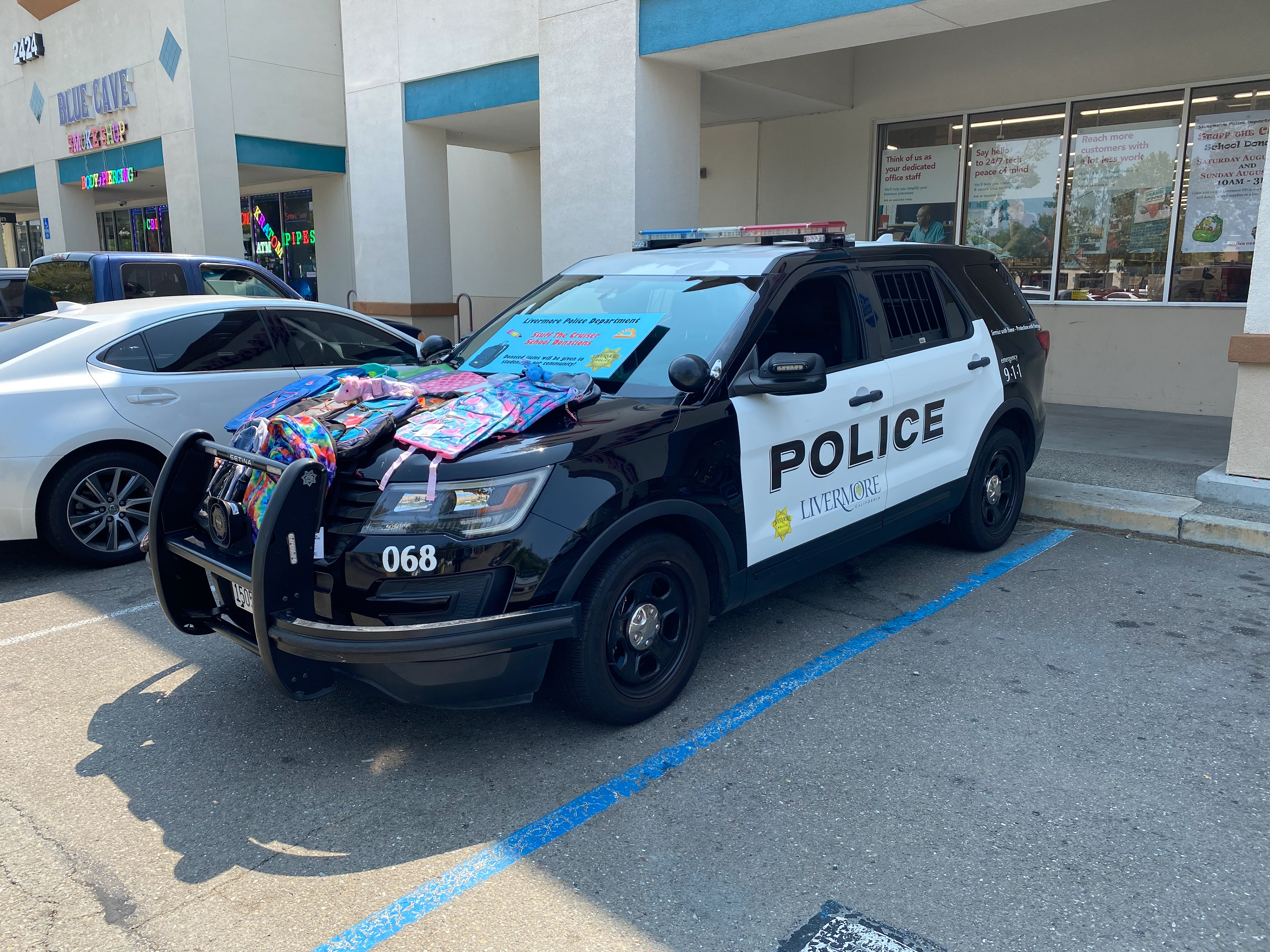 Livermore Police Cruiser vehicle with event sign on windshield and backpacks on the front hood.