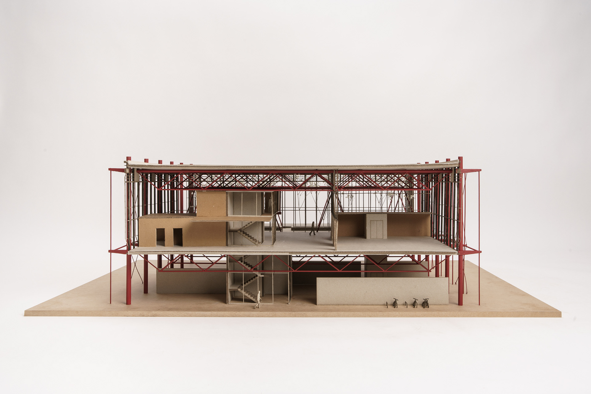 Geöffnetes Architekturmodell im Querschnitt: aufgeständerte Halle mit durchfahrbarem Erdgeschoss, Werkstattebene und Galerien