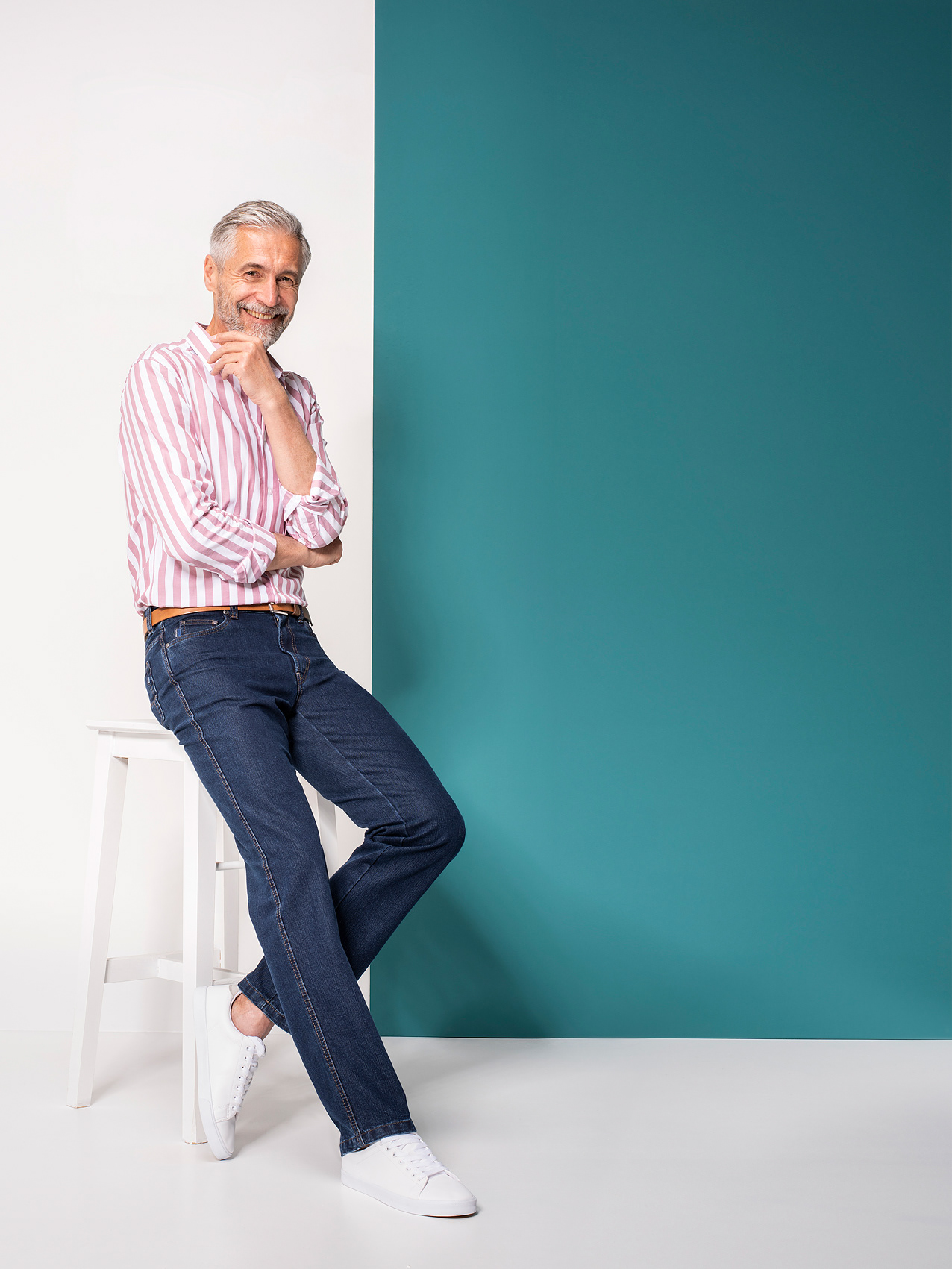 Lachender Mann auf weißem Hocker Mode Fotografie