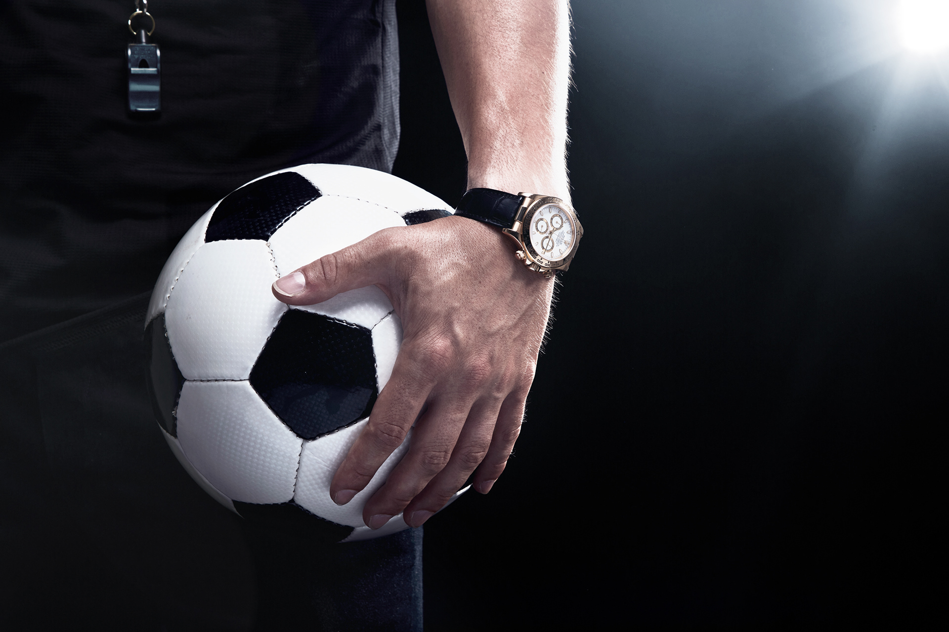 schiedsrichter mit ball im arm und goldener rolex daytona produktfotografie