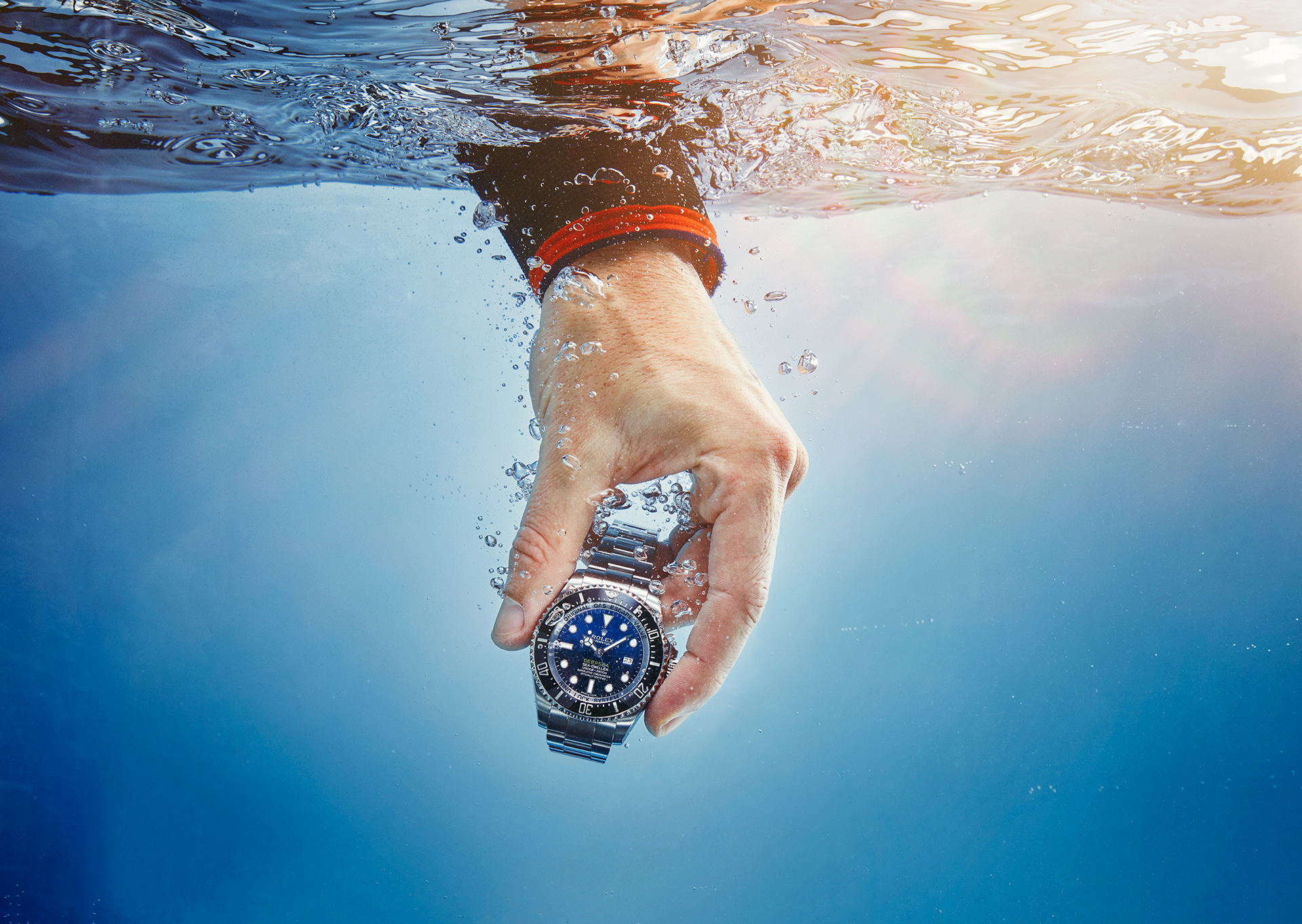 hand haelt eine rolex deepsea luxusuhr unter wasser