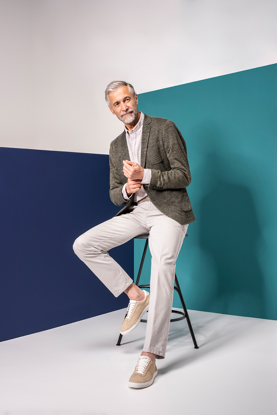 Mann auf Hocker vor blauer und türkiser Wand