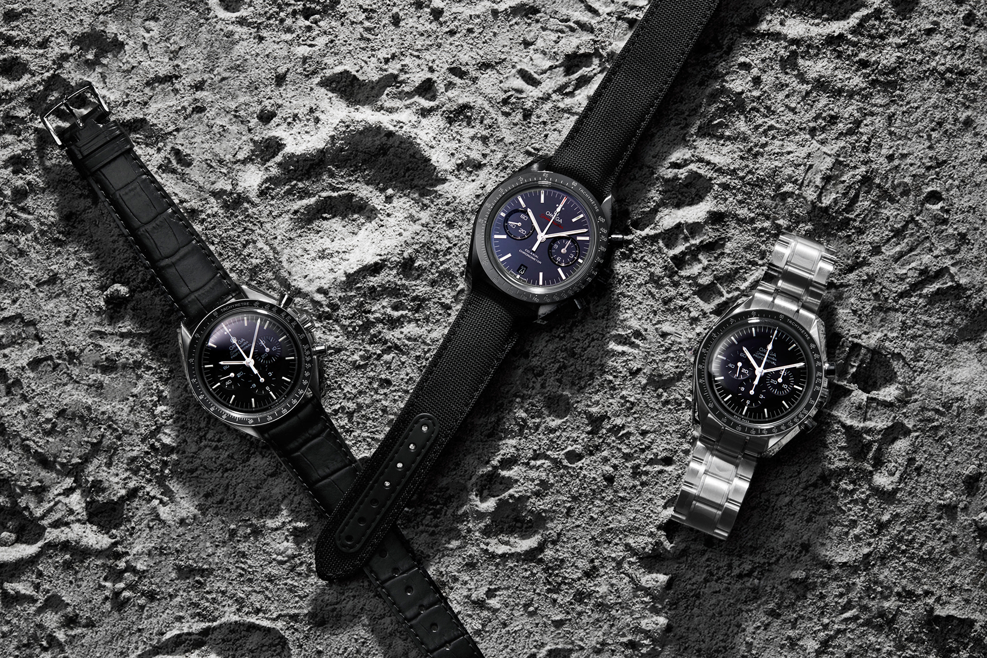 produktfotografie mehrerer omega speedmaster luxusuhren auf mondoberfläche