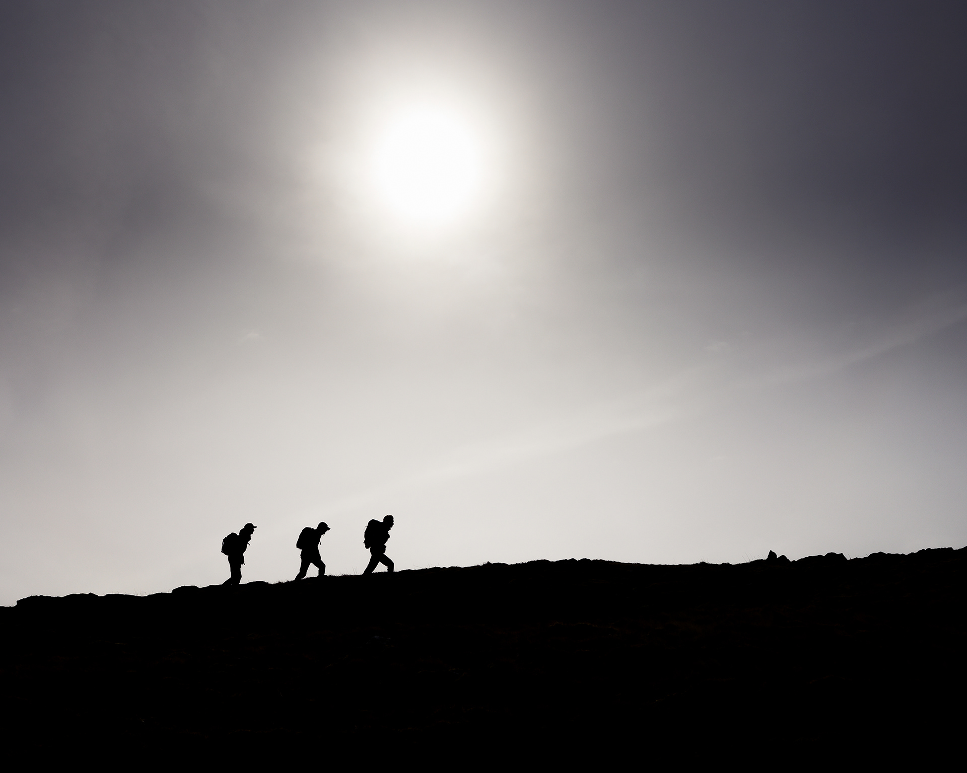 Under the Helvellyn Sun. Celyn, Jay, Jacob, and I took a short trip to the Lake District in March. We weren't looking to get any specific shots out of the journey as we were more catching up and exploring the Lakes, somewhere none of us knew. I shot this looking up at the others, using the sun to backlight them, creating a beautiful silhouette as we climbed up Helvellyn.