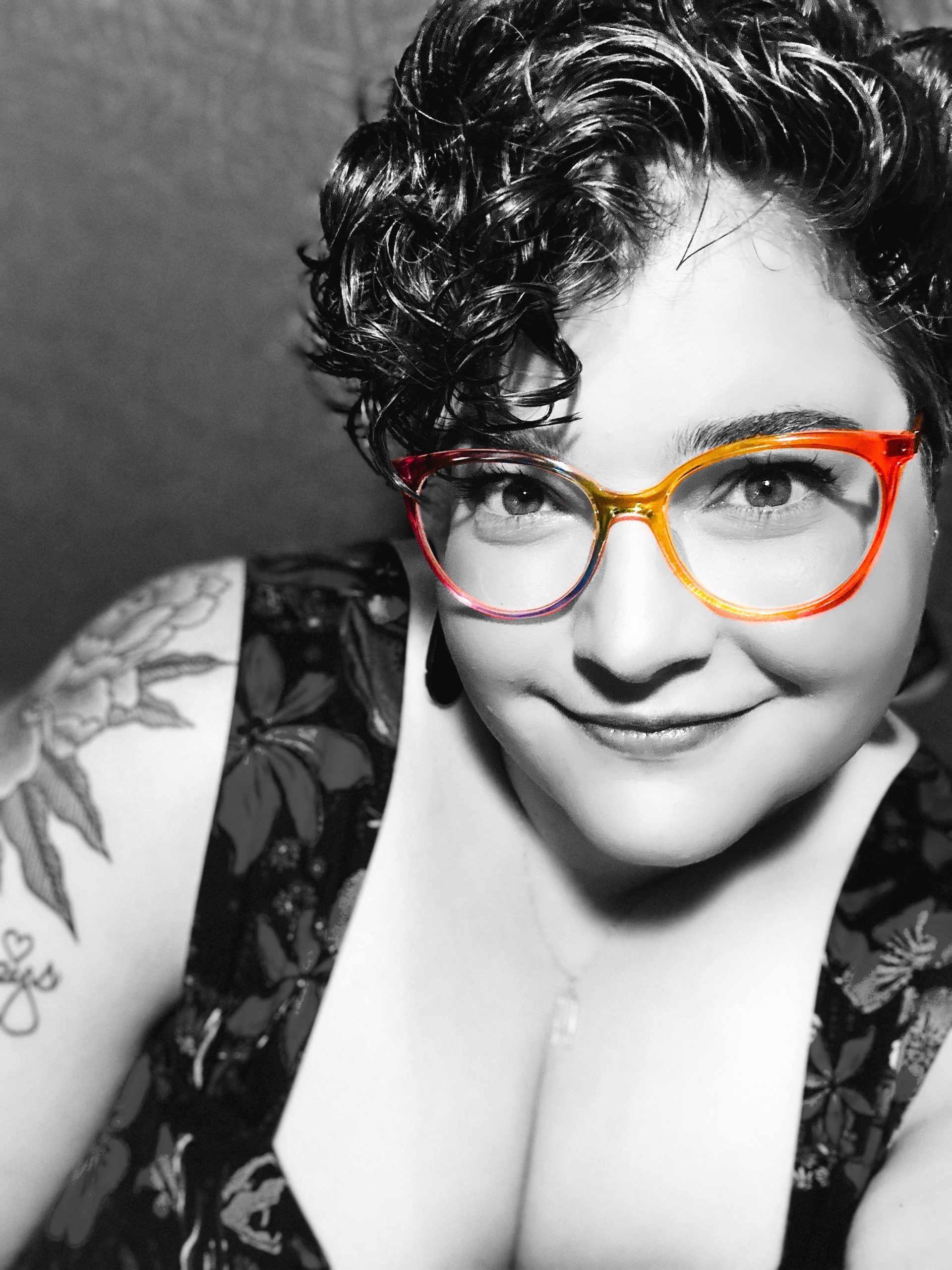Monochrome portrait of Angela Spinzig. Eyeglasses appear as a pop of color.