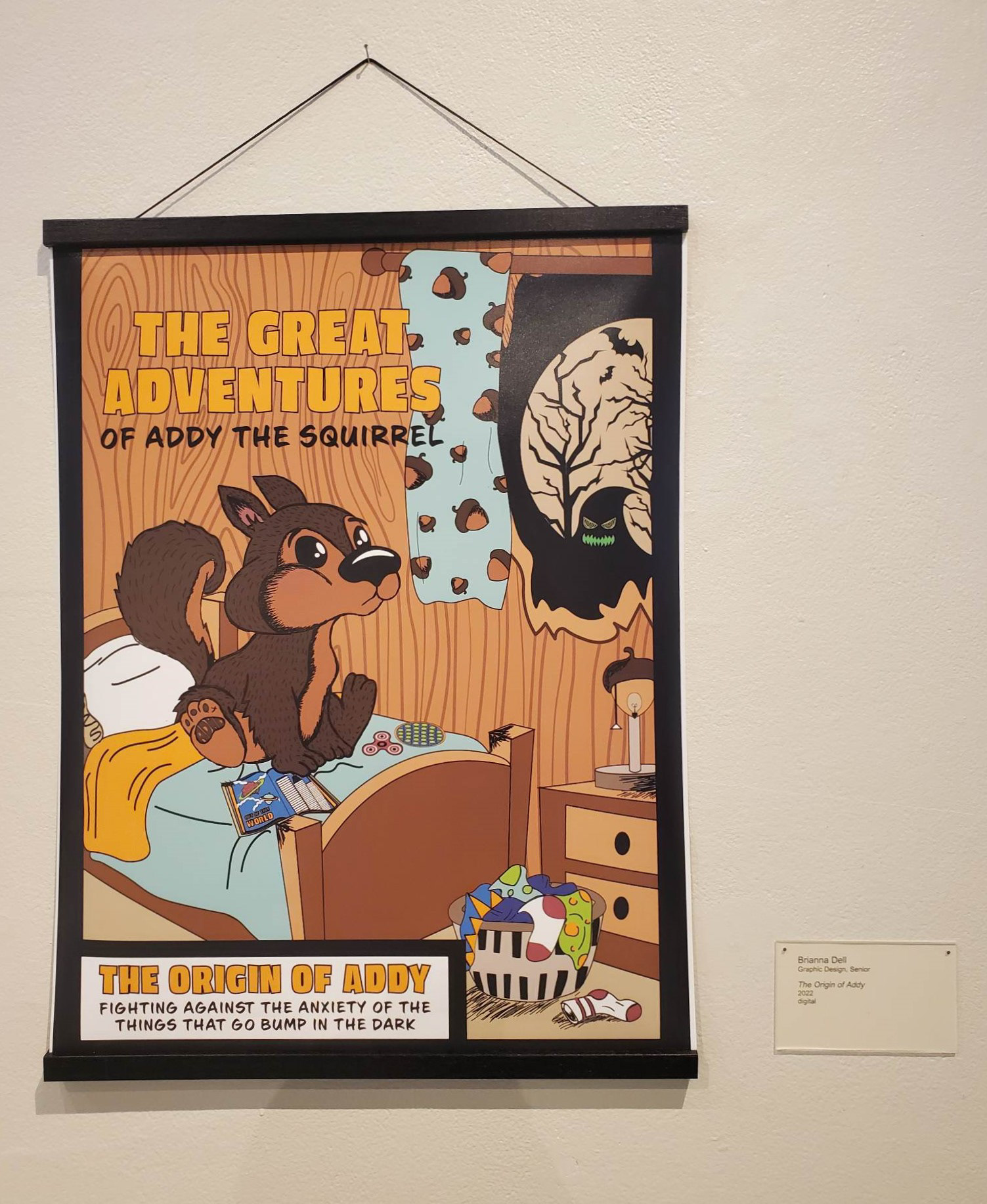 A photo of my Origin of Addy poster being hung at the CMU Student Art Exhibit 2023