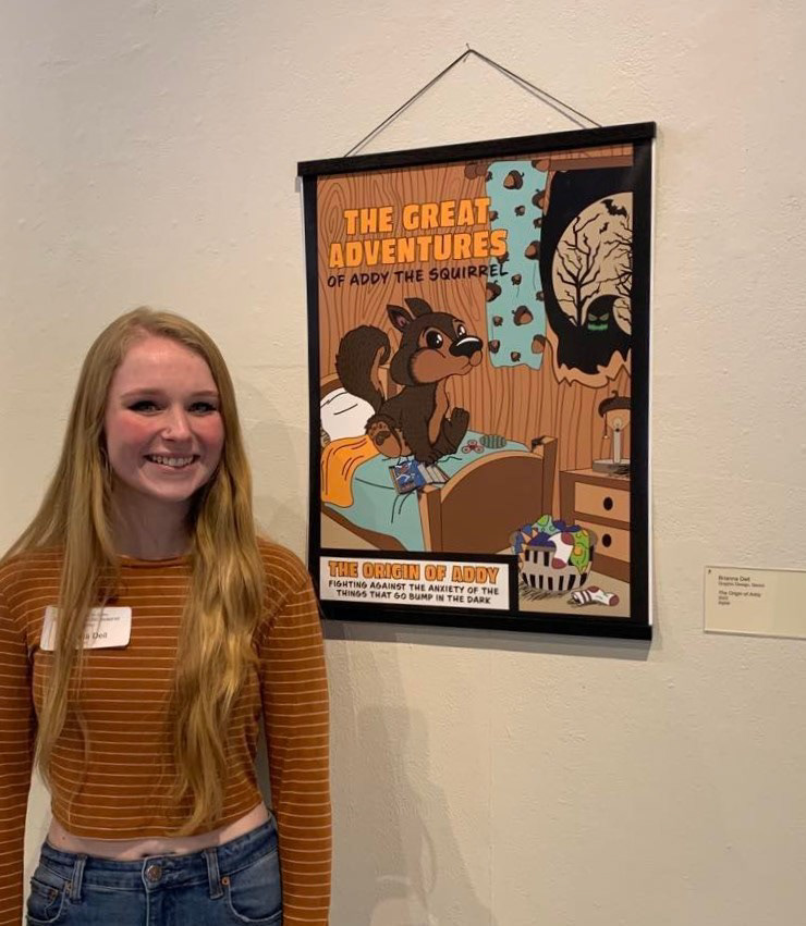 A photo of me with my Origin of Addy poster at the CMU Student Art Exhibit 2023