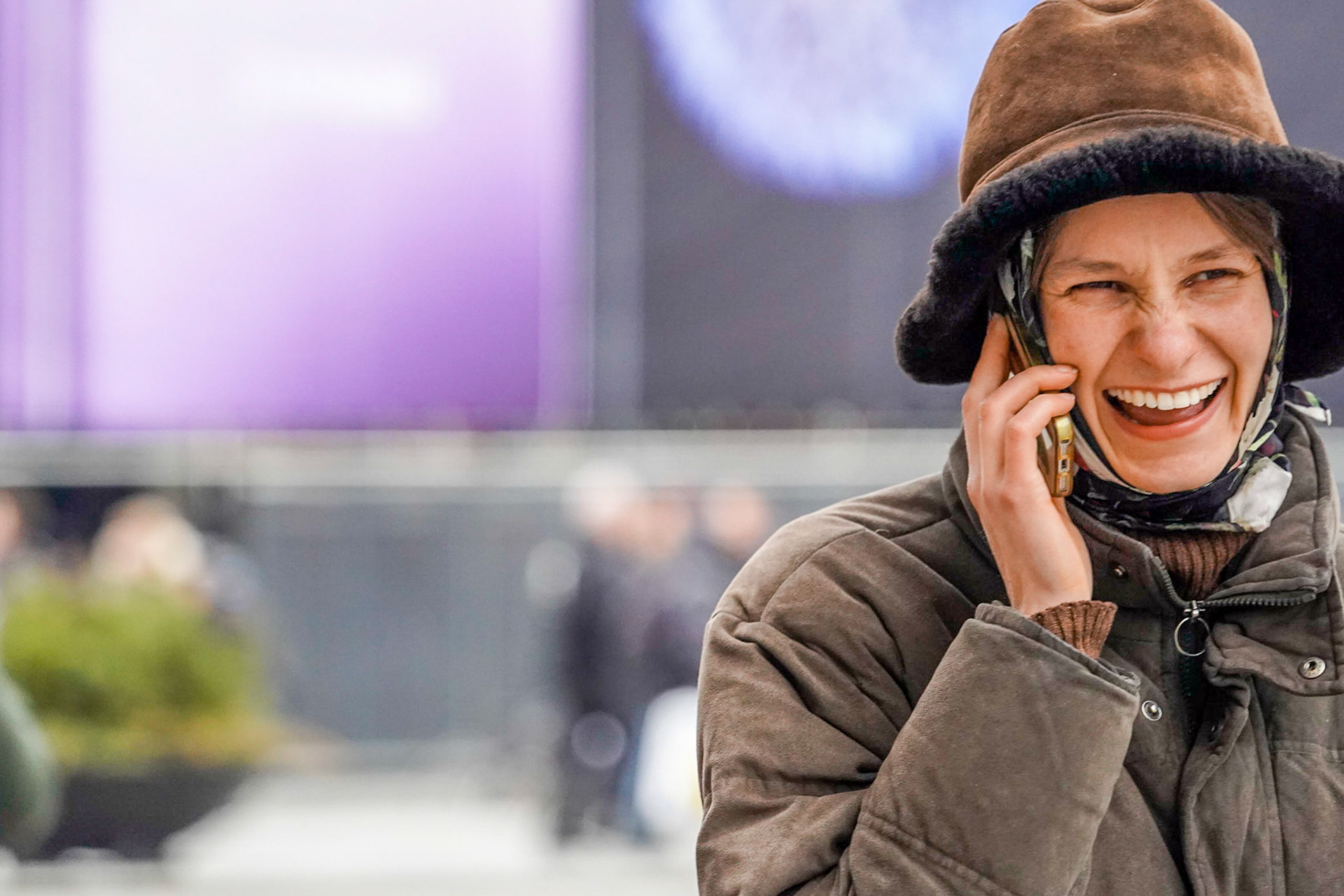Young well dressed woman talking on her mobile phone on the street in Copenhagen, smiling and laughing