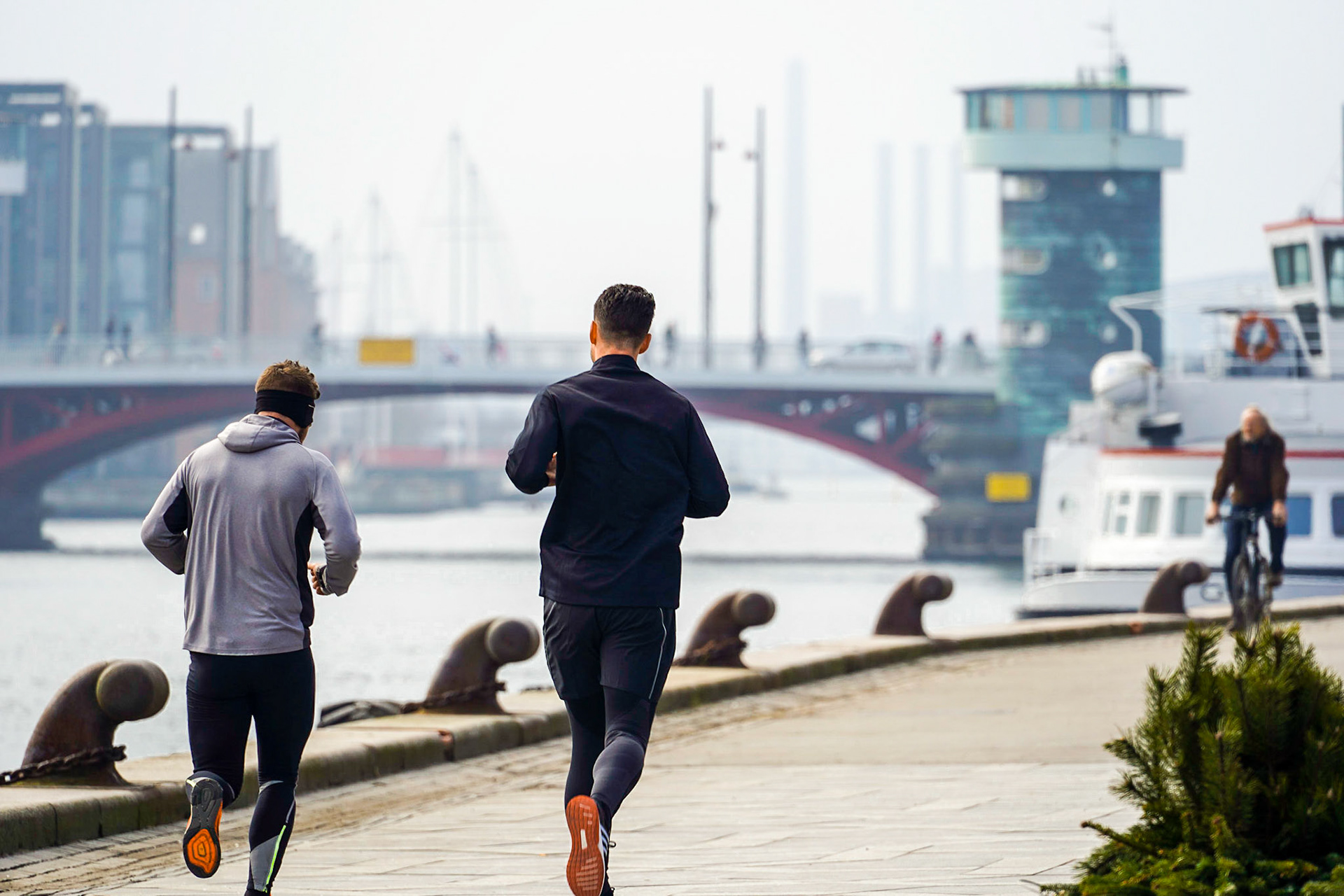 Runners on boardwalk by the Copenhagen Waterfront, Knippelsbro (Knippel's Bridge) and Cirkelbroen (Circle Bridge) in the background