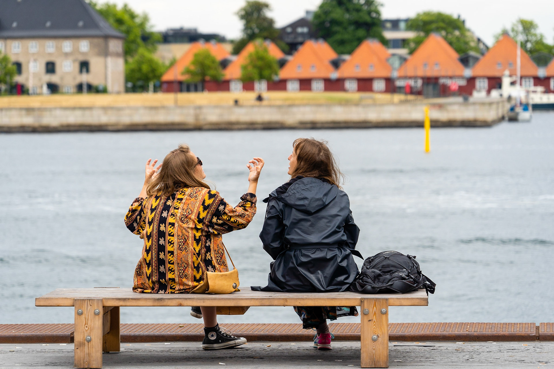 Two young women talking on bench on Ofelia Square (Ofelias Plads) by the Copenhagen waterfront